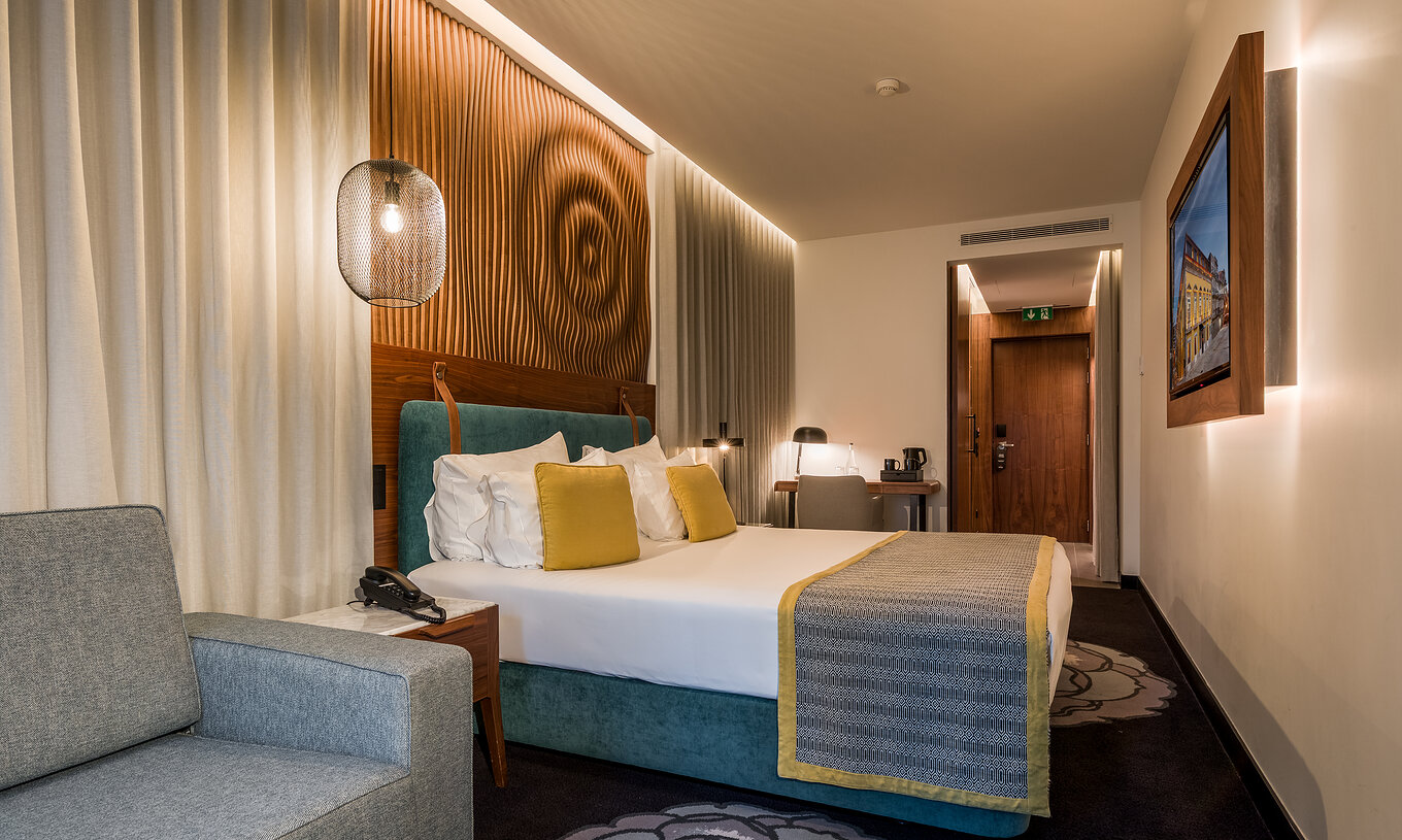 The Superior Family at Pousada Porto - Rua das Flores has a double bed with bedside tables and a grey sofa.