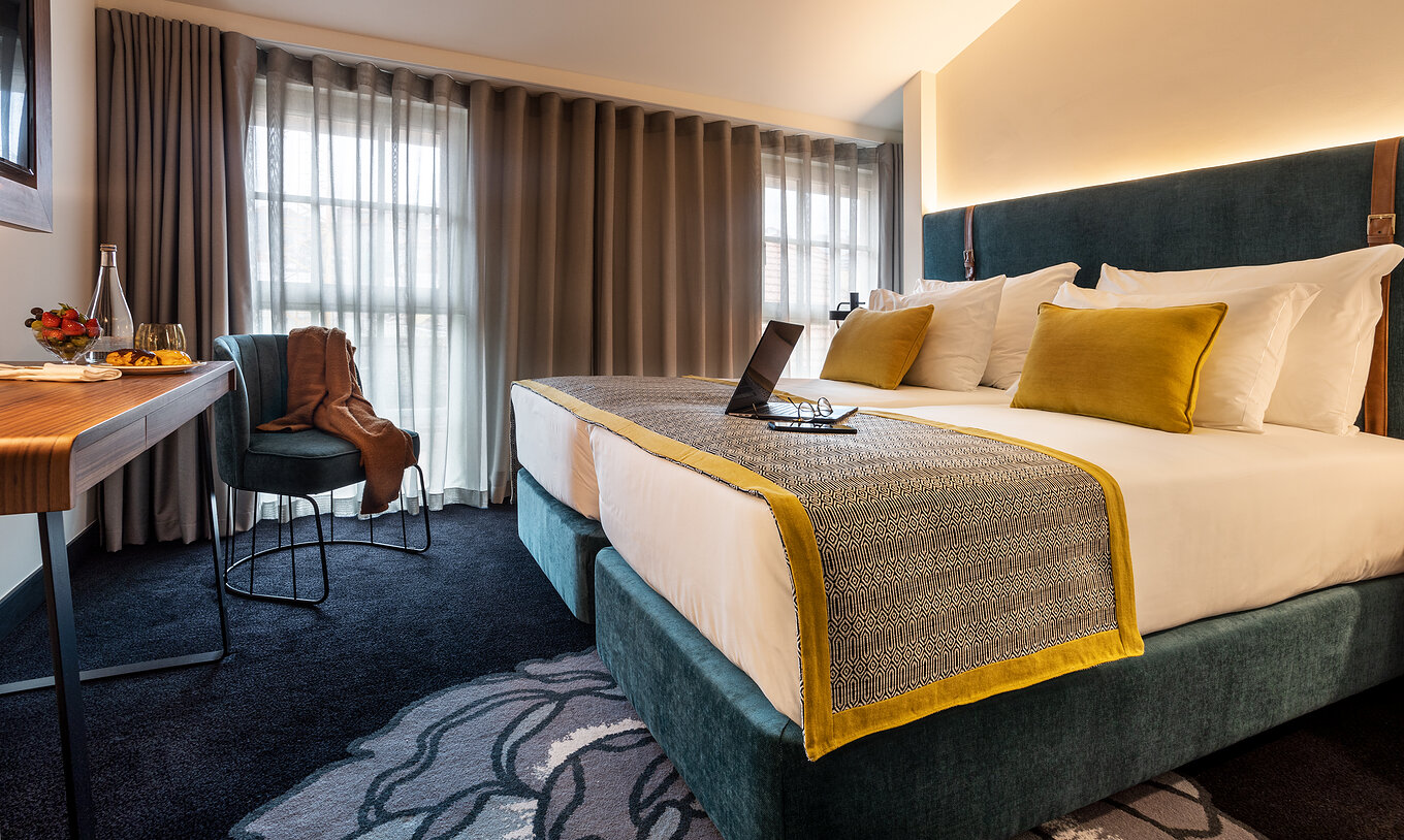 The Superior Plus Room of The Porto Inn - Rua das Flores has a turquoise double bed, white sheets, and a table