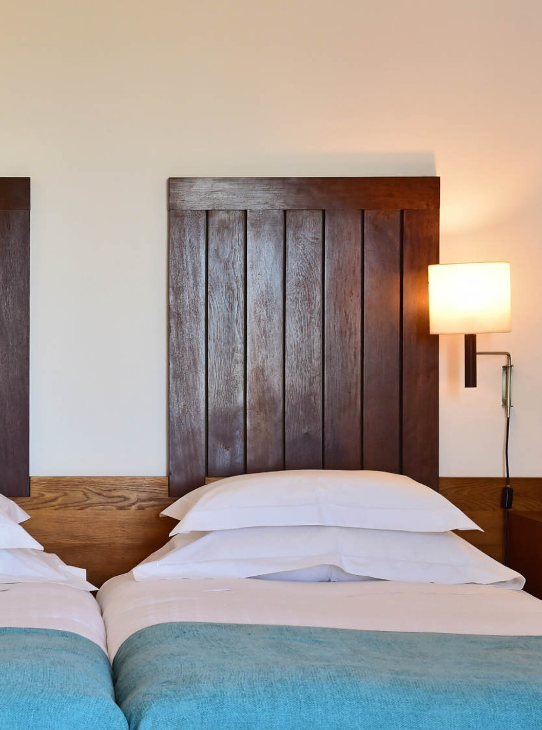 The Classic Family Room of the Pousada Castelo Alcácer do Sal has two beds, with a blue blanket and a wooden headboard