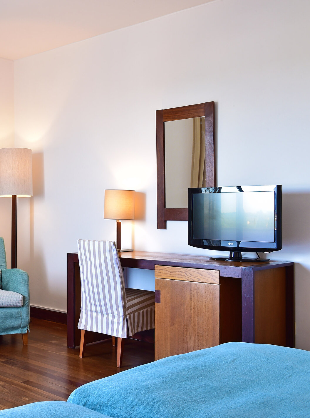 The Classic Family Room of the Pousada Castelo Alcácer do Sal has a desk with a television and two blue armchairs