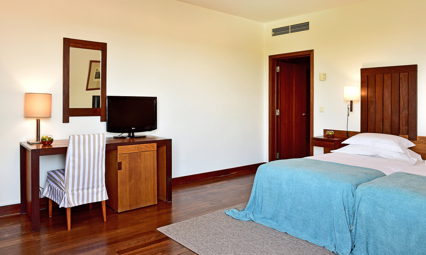 The Classic Room of the Pousada Castelo Alcácer do Sal has a desk with a television and two separate beds