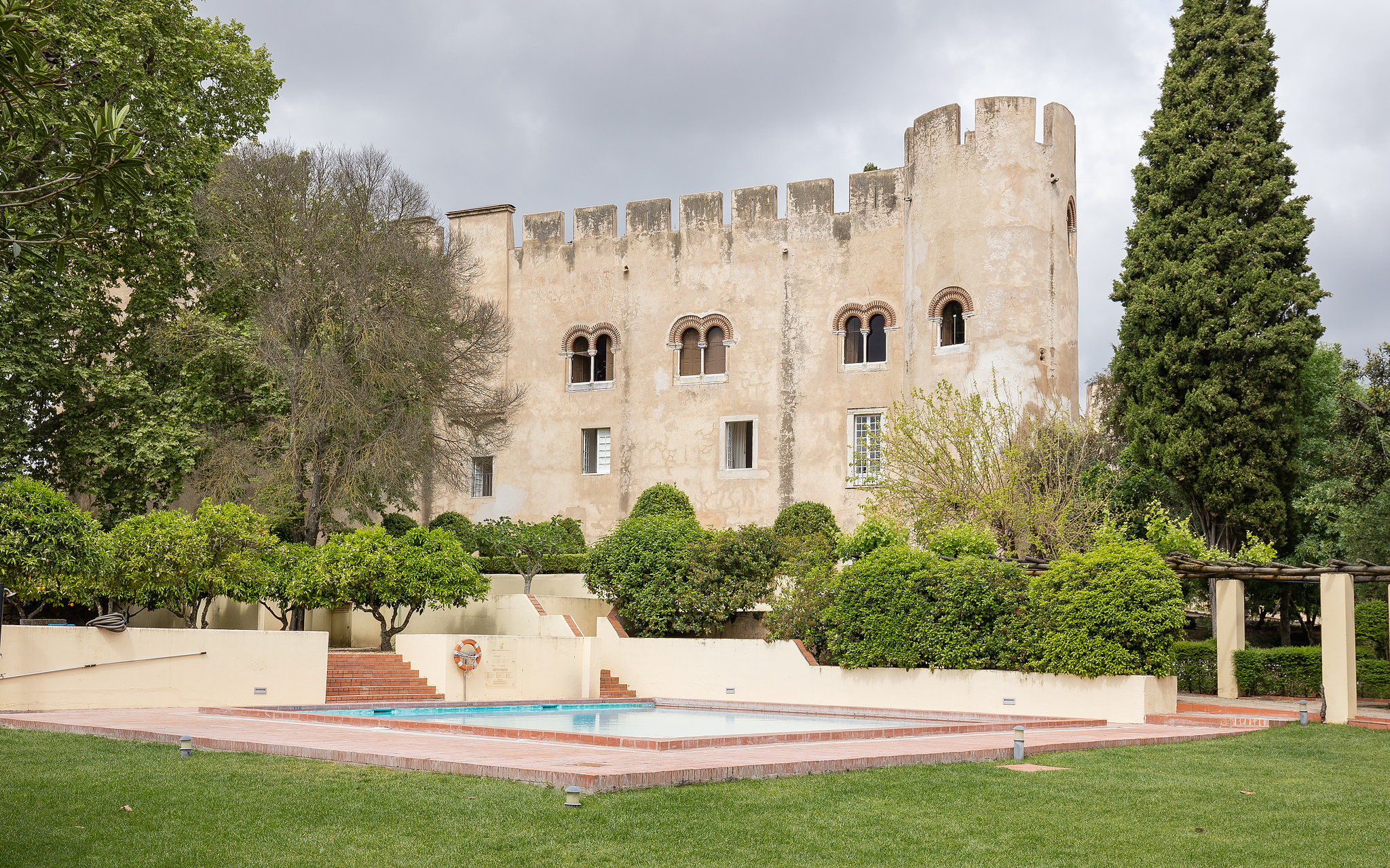 Exterior view of Pousada Castelo Alvito, a historic hotel in Alvito, with an outdoor pool and the castle in the background