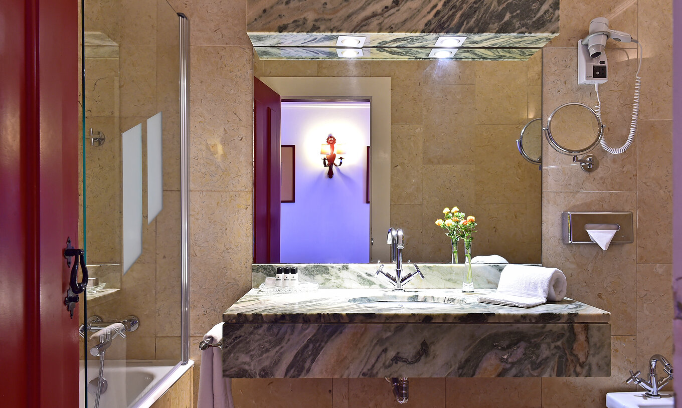 The Family Room of The Pousada Convento Beja has a counter with a sink, a large mirror, and a decorative flower