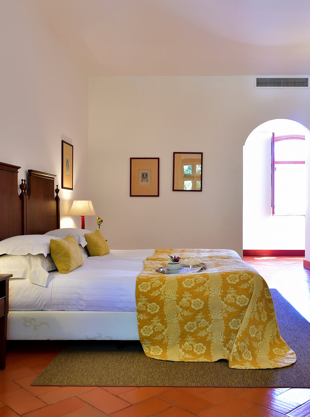 The Family Room of The Pousada Convento Beja has two beds, two bedside tables, and a television