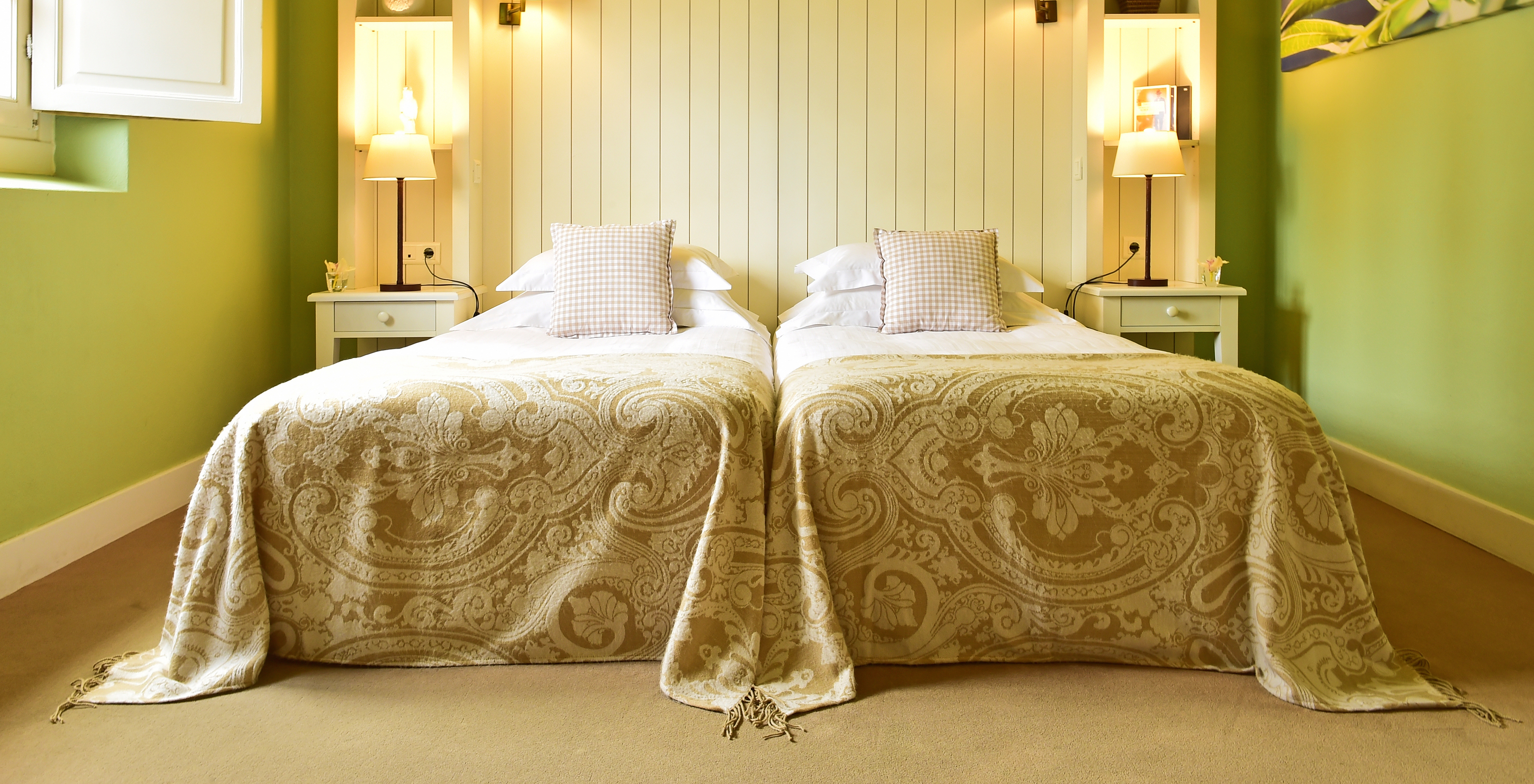 The Classic Room of The Pousada Convento Évora has two separate beds with a beige patterned bedspread and green walls