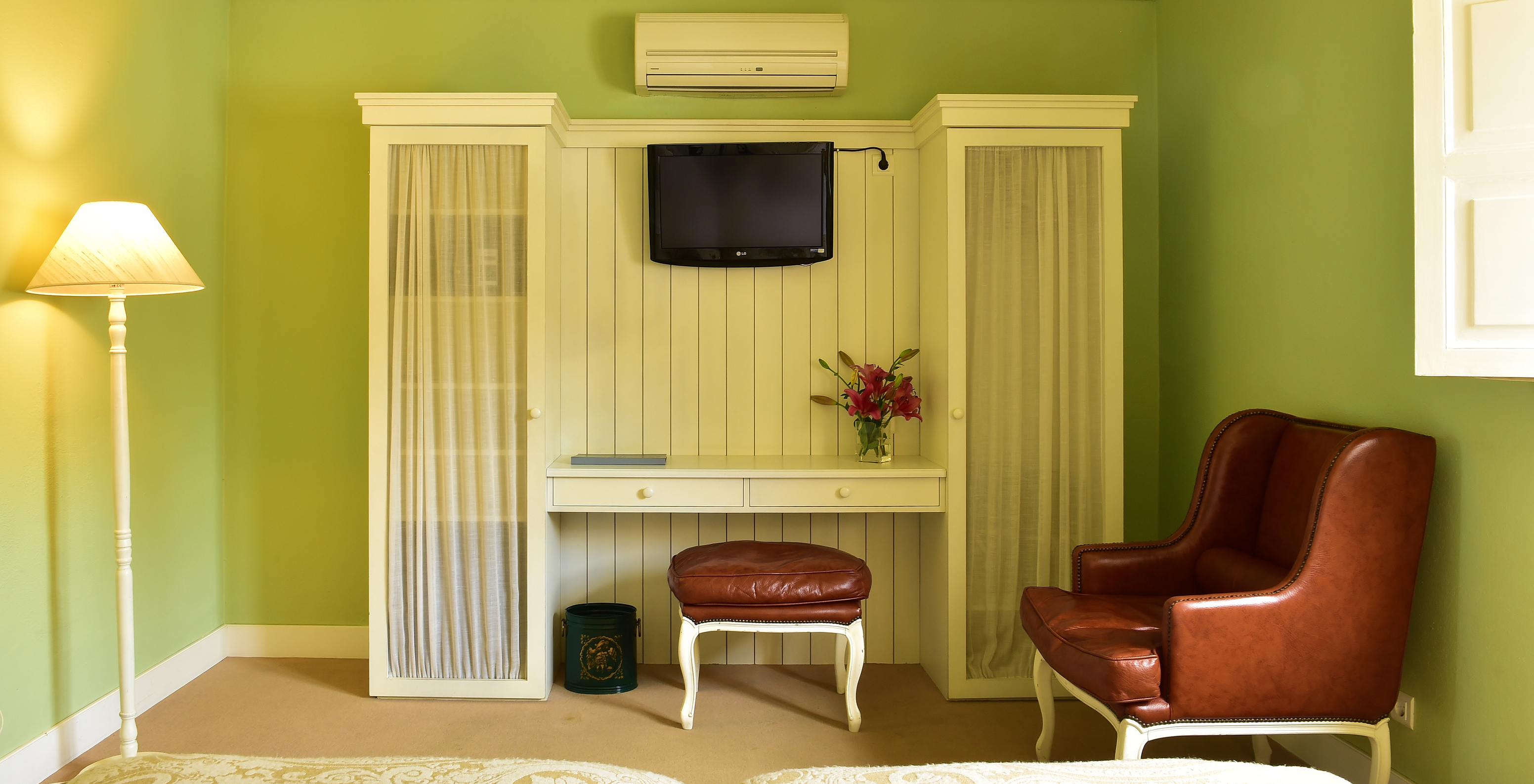 The Cozy Room of The Pousada Convento Évora has a mounted television, an armchair, and a desk