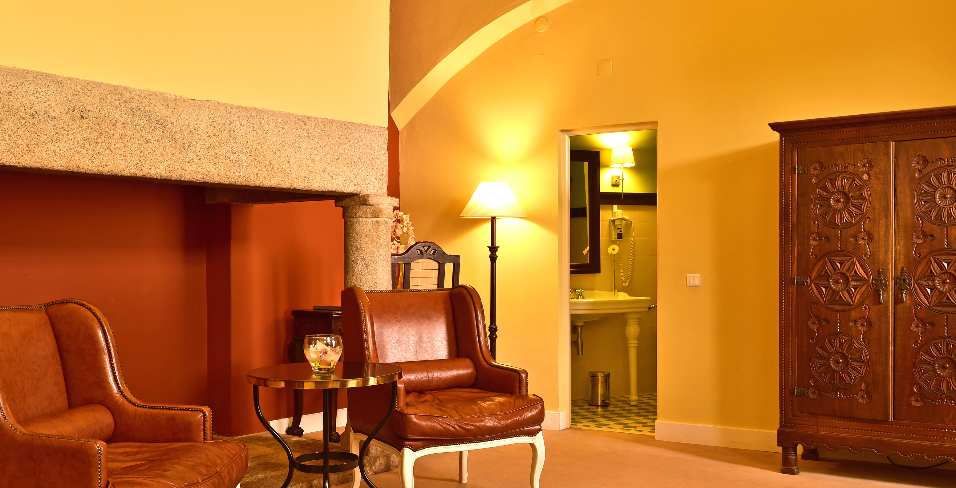 The Superior Family of The Pousada Convento Évora has two leather armchairs, a bathroom, and a wooden wardrobe