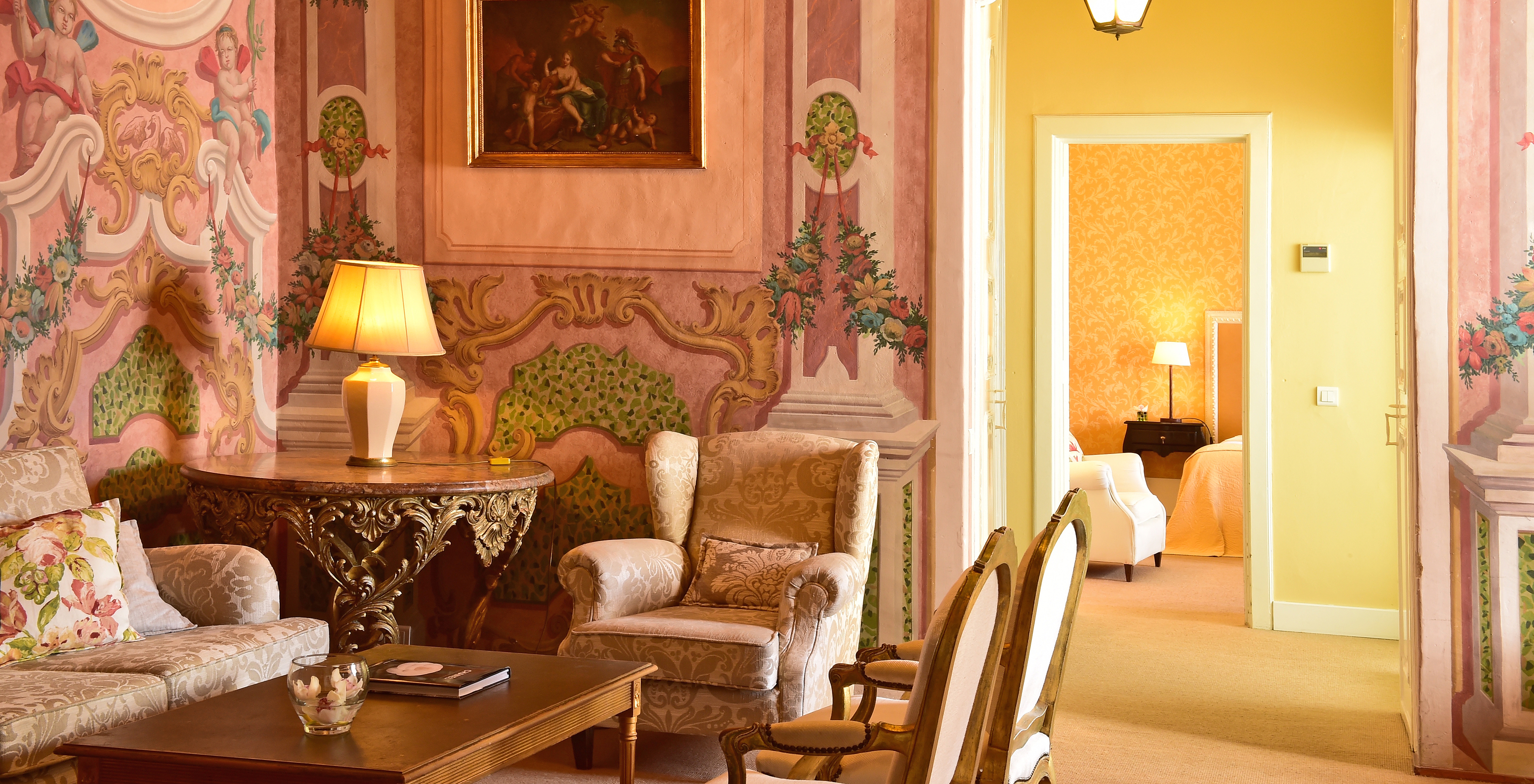 The Master Suite of The Pousada Convento Évora has a living room with a sofa and an armchair and a bed in the background