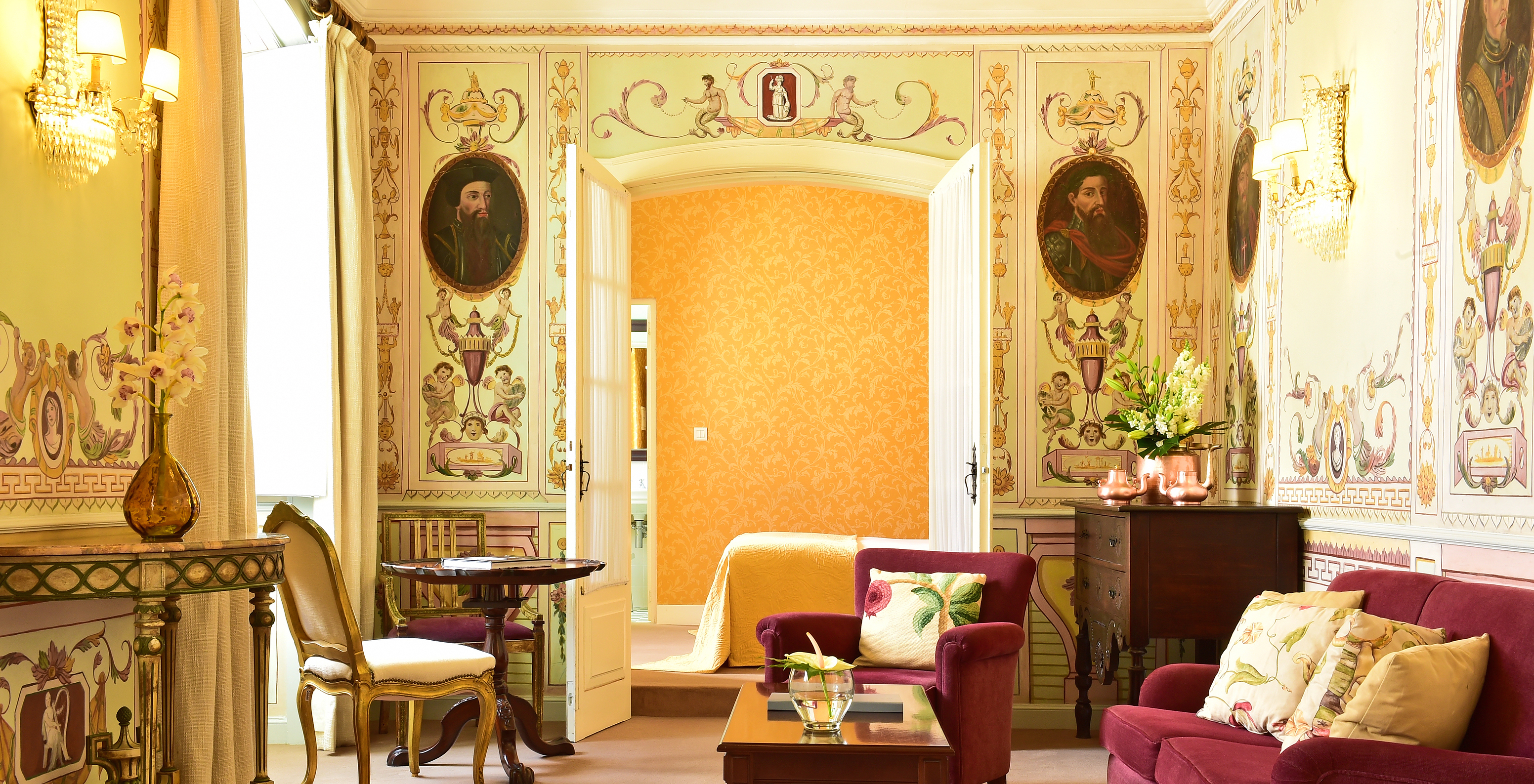 The Special Suite of The Pousada Convento Évora has a living room with a sofa and an armchair and a bed in the background