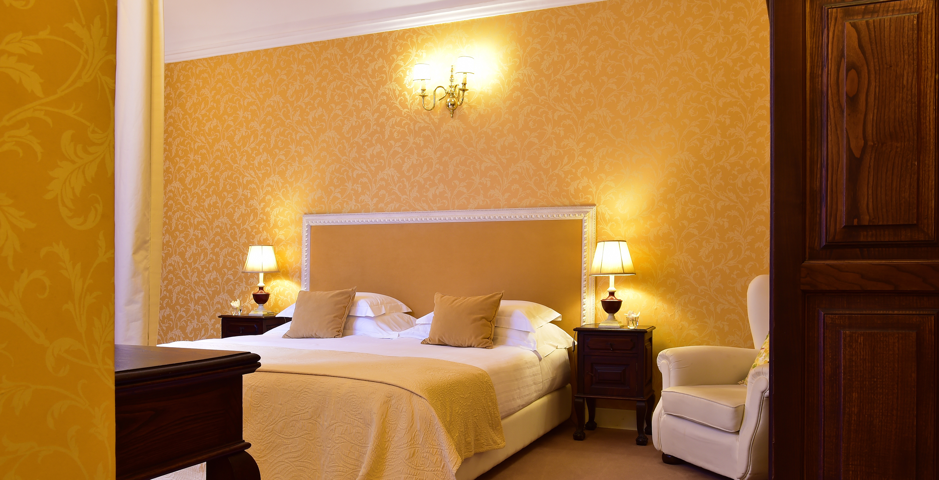 The Suite of The Pousada Convento Évora has a double bed with two bedside tables and an armchair