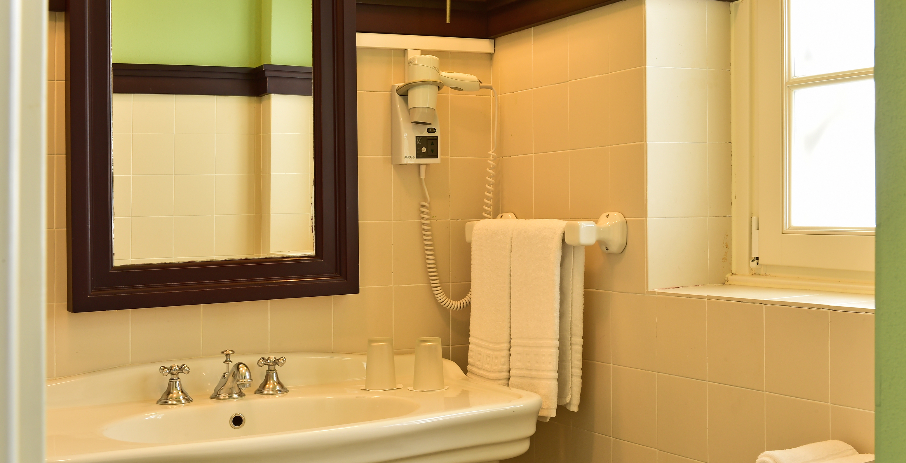 The Superior Room of The Pousada Convento Évora has a bathroom with a sink and a wooden-framed mirror