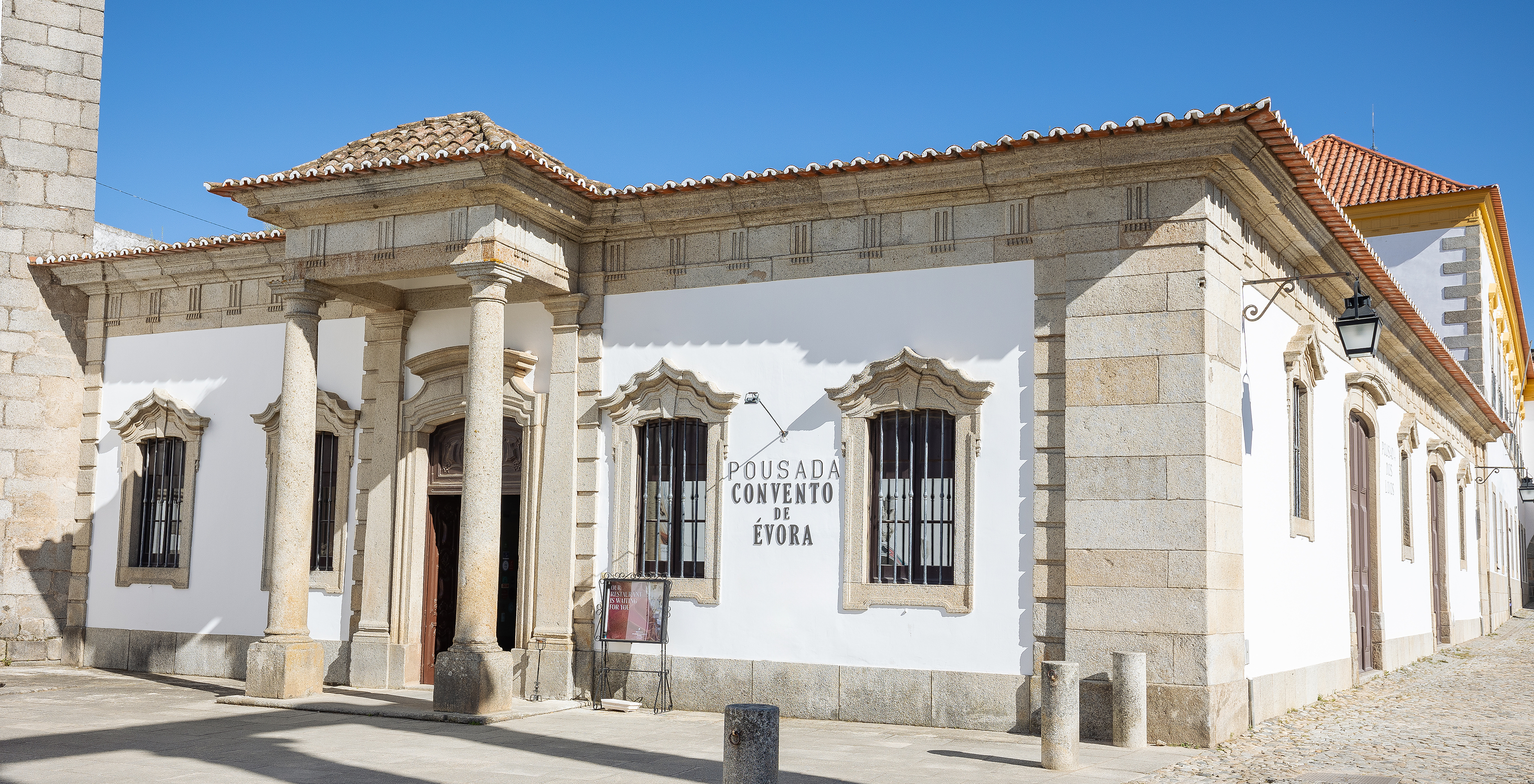 Exterior view of Pousada Convento Évora, with white walls and stone details