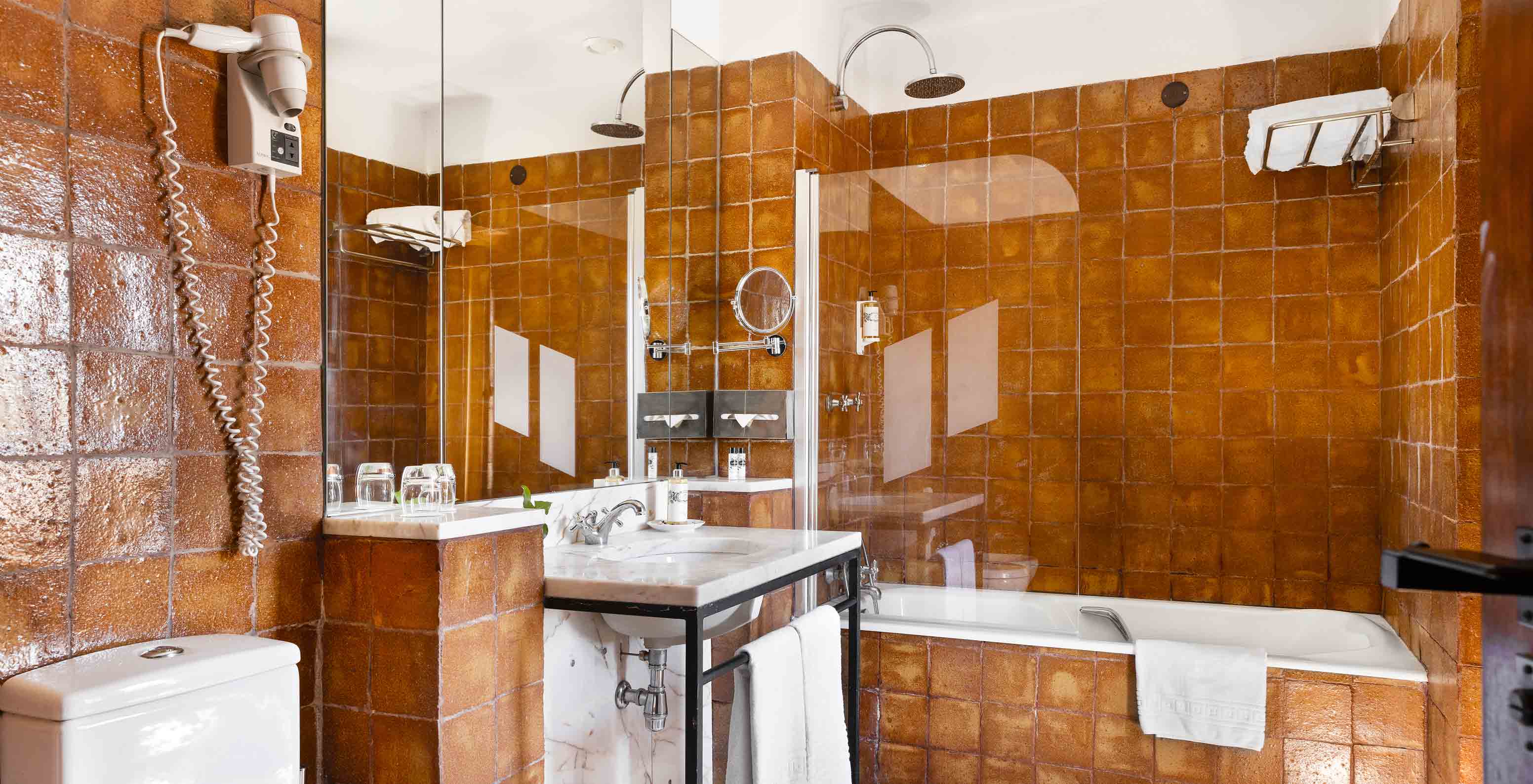 The suite at Pousada Convento Vila Viçosa has a bathroom with bathtub, sink, mirror, towels and hairdryer