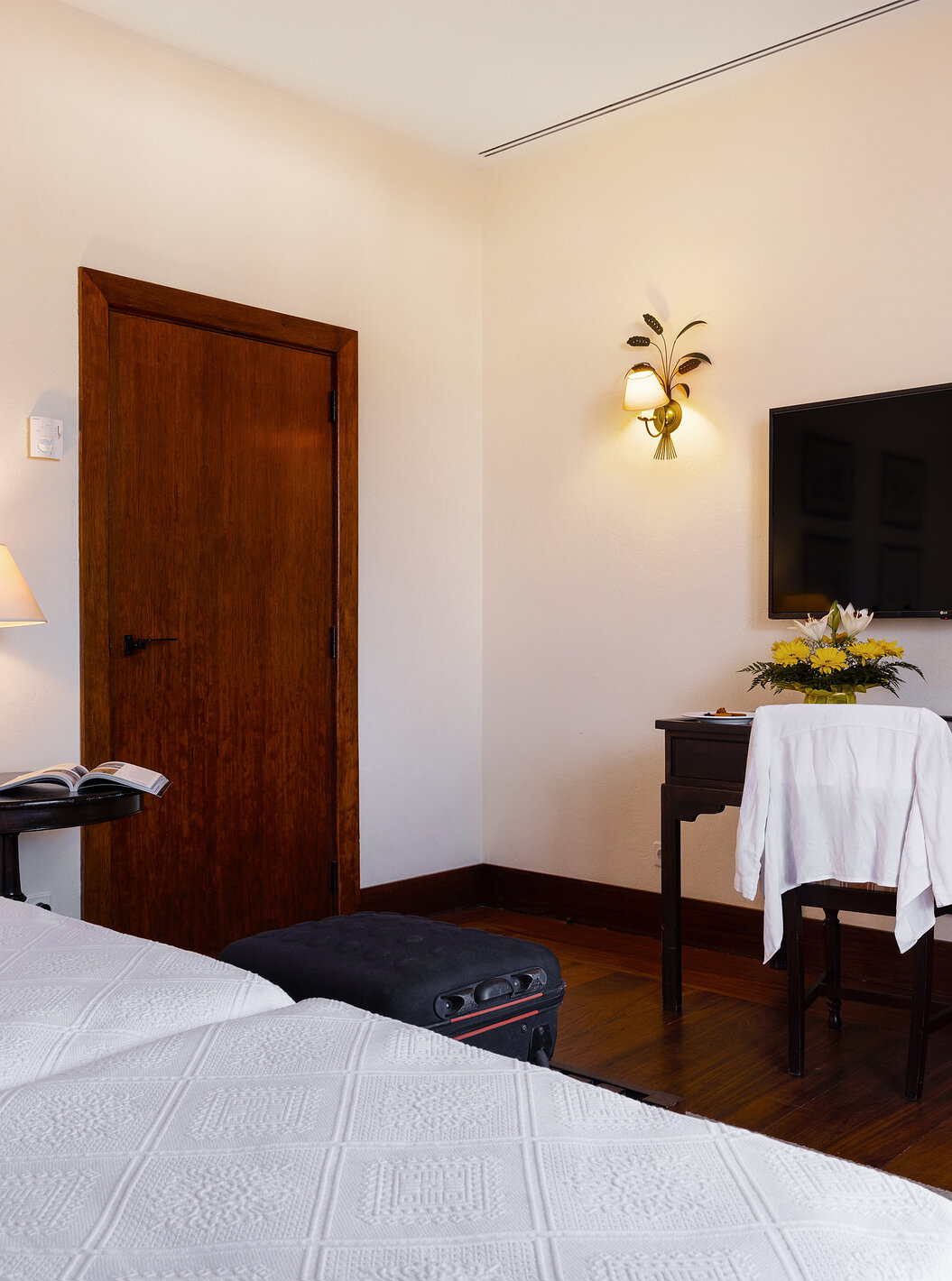 The Classic Room of The Pousada Convento Vila Viçosa has a door, two paintings, and a television in front of the beds