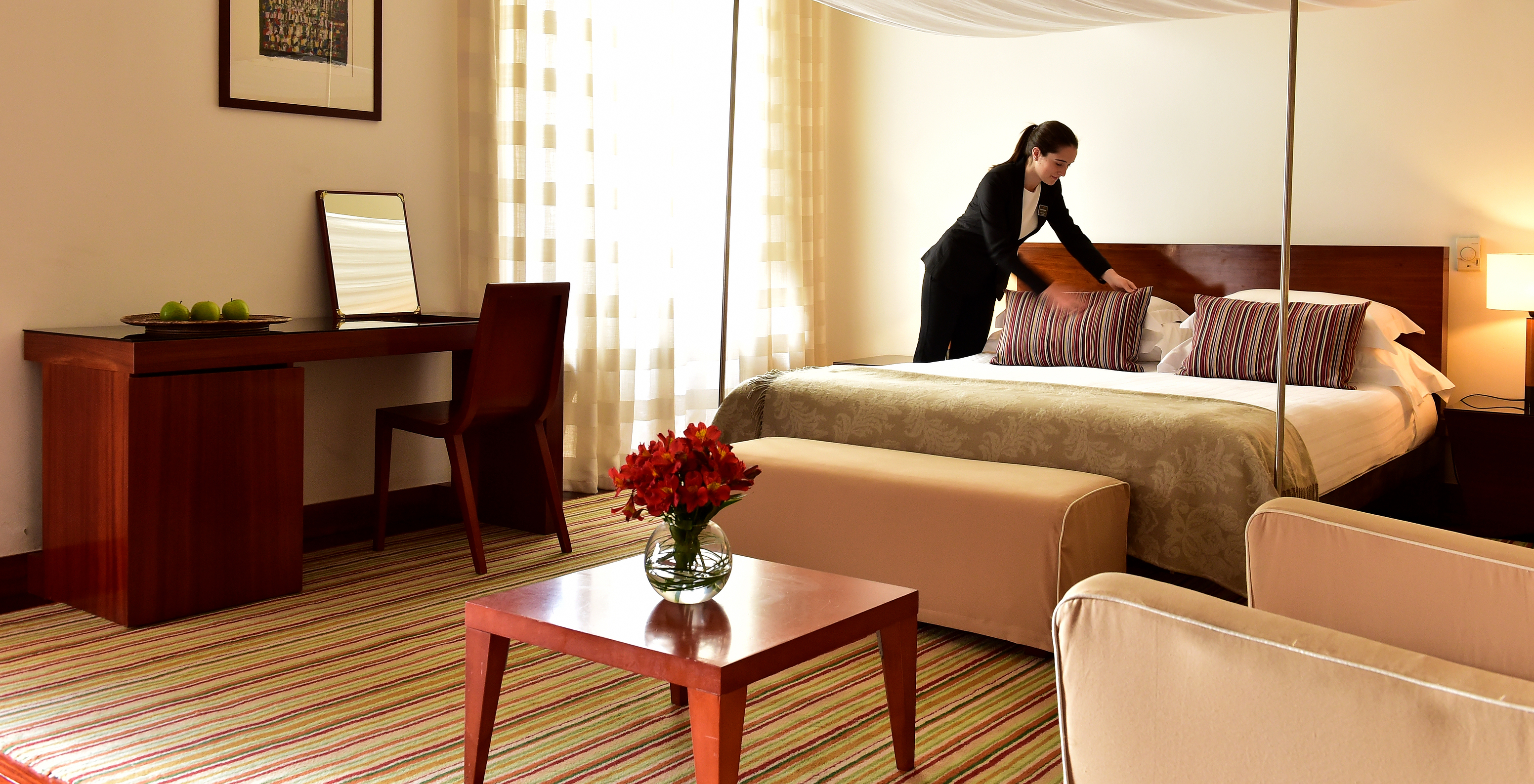 The Historical Superior Room of The Pousada Mosteiro Crato has stone walls with a four-poster bed, a sofa, and a desk