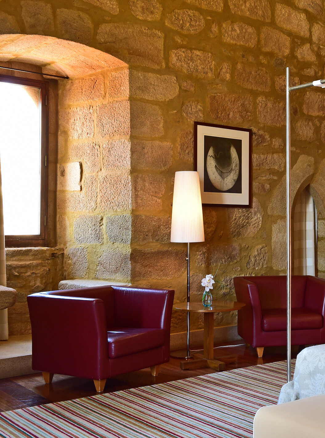 The Master Suite of The Pousada Mosteiro Crato features stone walls, a four-poster double bed, and two armchairs to relax