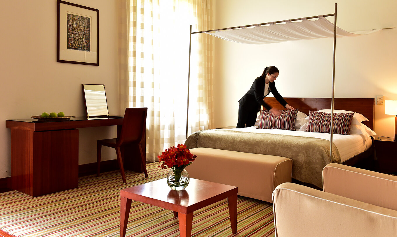 The Historical Superior Room of The Pousada Mosteiro Crato has stone walls with a four-poster bed, a sofa, and a desk