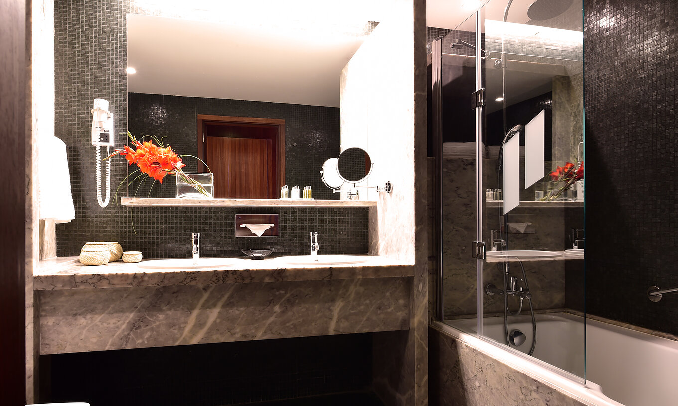The Superior Room of The Pousada Mosteiro Crato has a gray marble bathroom with a toilet, bathtub, and two sinks