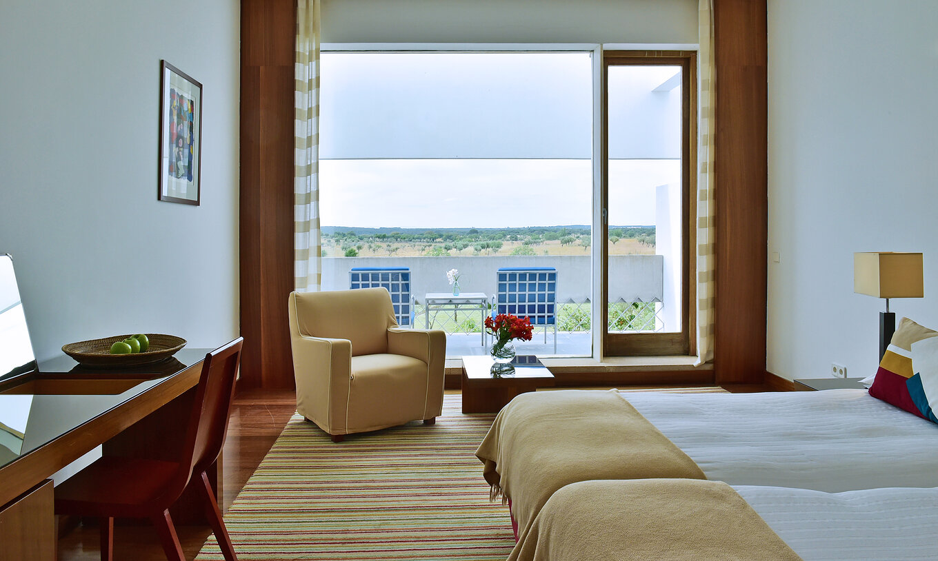 The Superior Room of The Pousada Mosteiro Crato has two joined single beds, an armchair, and a balcony with a table