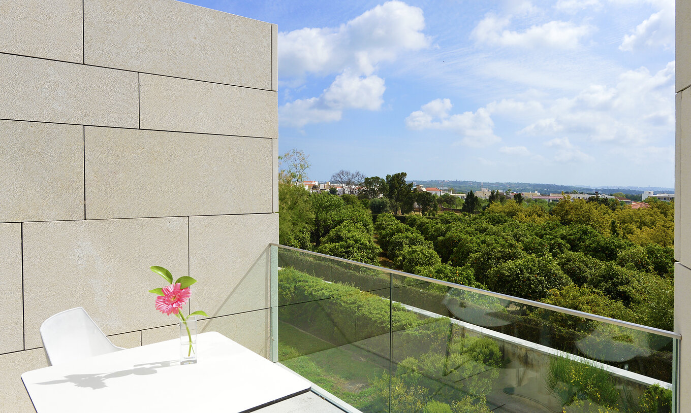 The Superior Room of The Pousada Palácio Estoi features a balcony with a table with a chair and a garden view
