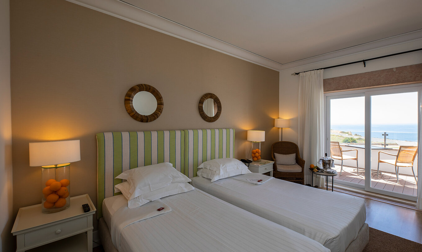 The Superior Premium Sea View Room of Pousada Sagres has two beds with striped headboards, two mirrors, and a balcony