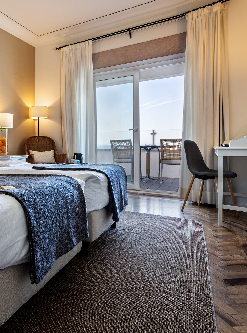 The Superior Sea View Room of Pousada Sagres has two beds with striped headboards, two round mirrors, and a balcony