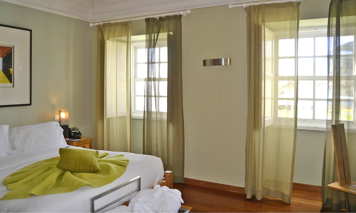 The Standard Suite of The Pousada Forte Angra do Heroísmo has two windows next to the bed with a sea view