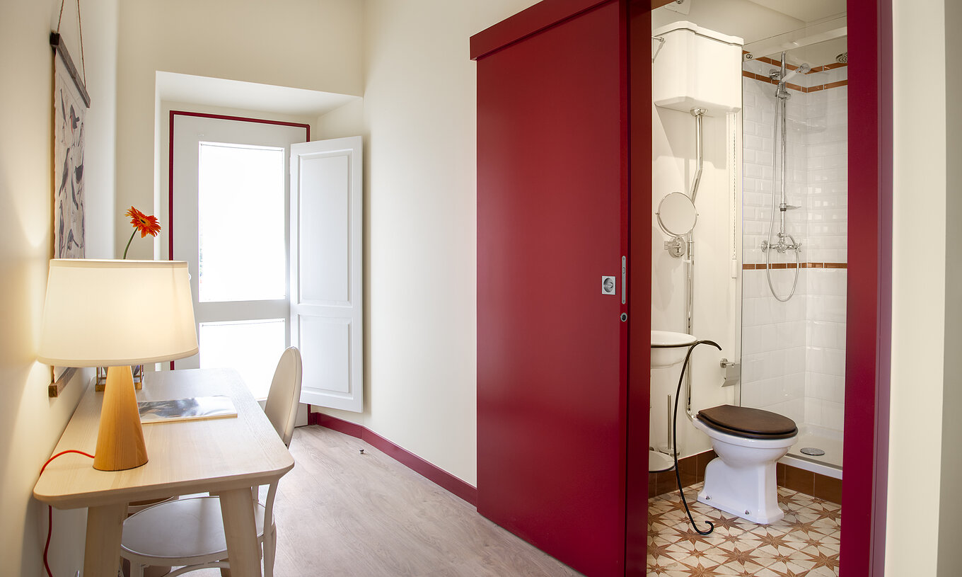 The Superior Room at Casa Lidador - Óbidos has a red sliding door bathroom, sink, toilet, and shower