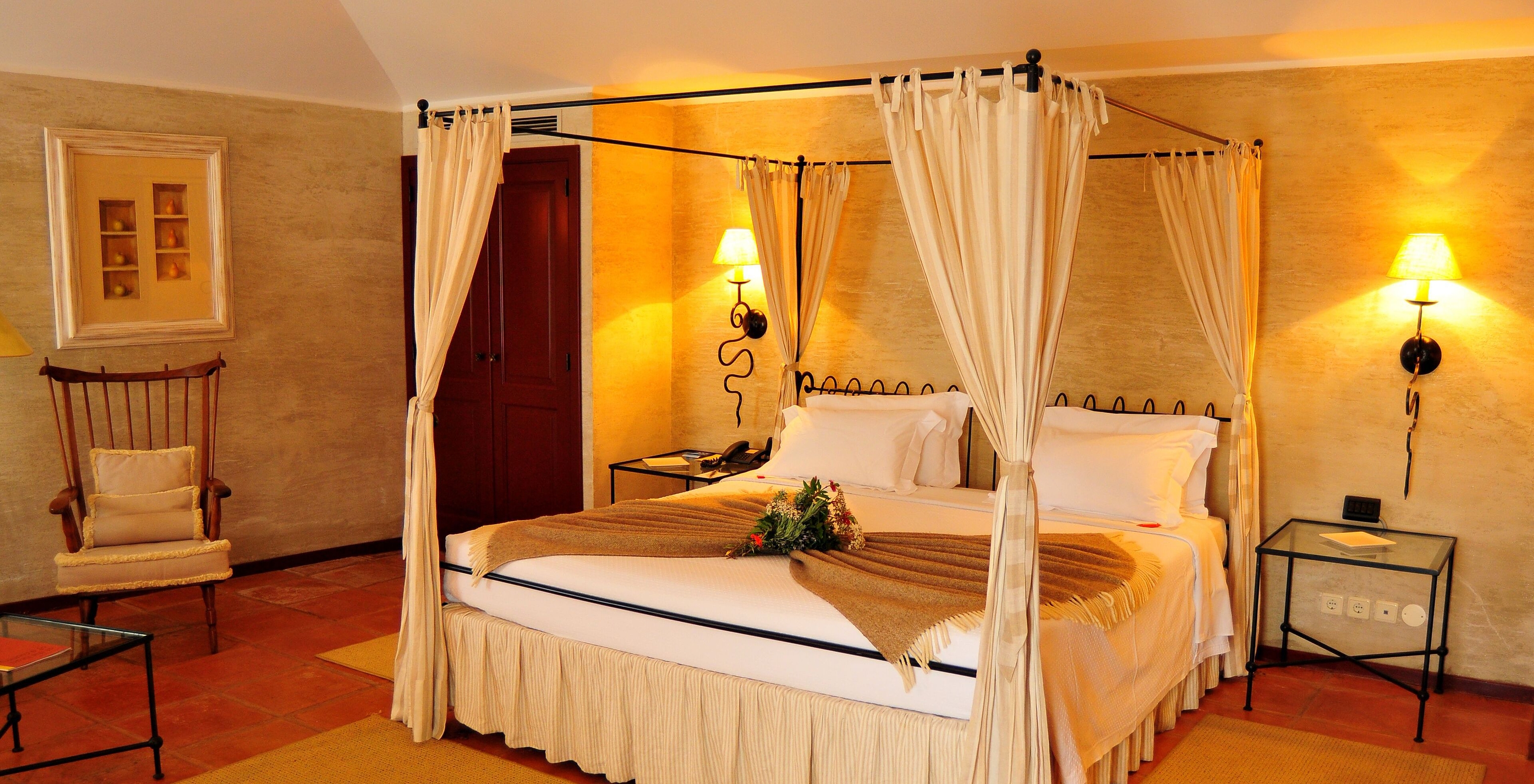 The Superior Room of The Pousada Convento de Belmonte has a double bed with a blanket and flowers on the bed