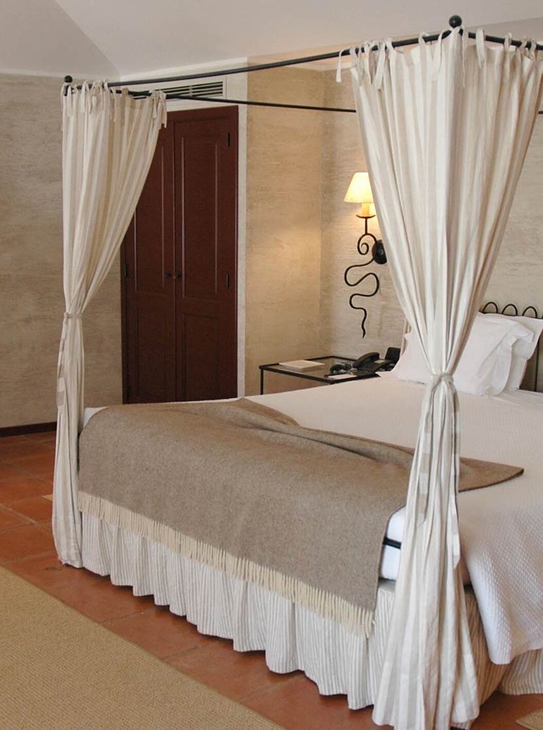The Deluxe Room of The Pousada Convento de Belmonte has a double bed with a brown blanket and two pillows