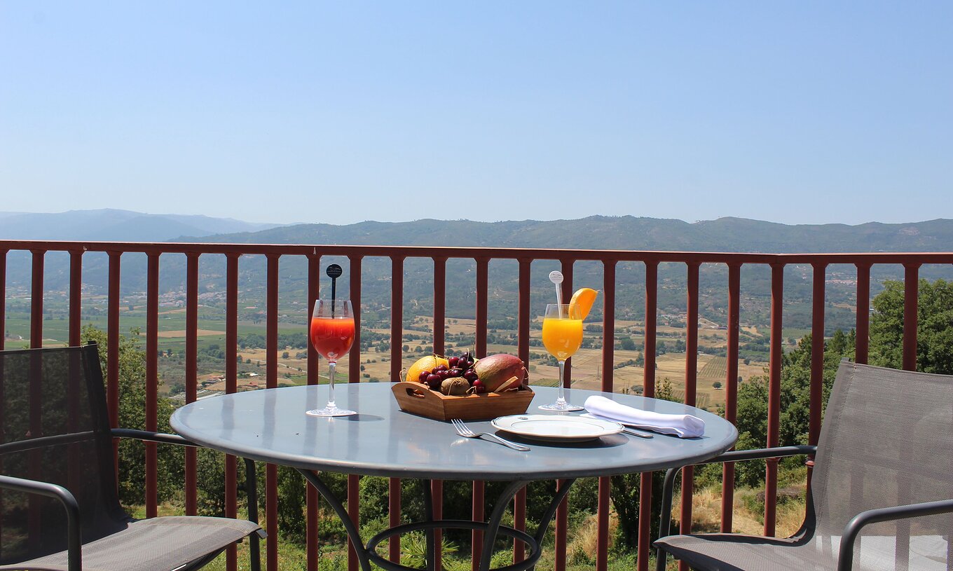 The Twin Room with Balcony of The Pousada Convento de Belmonte has a table set with two juices and an impressive view