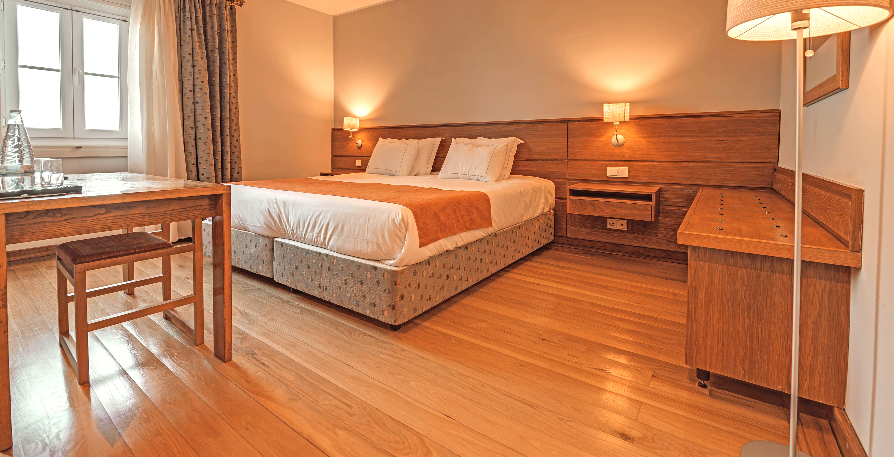 The Superior Room of The Pousada Ourém features a double bed with two bedside tables and a side table