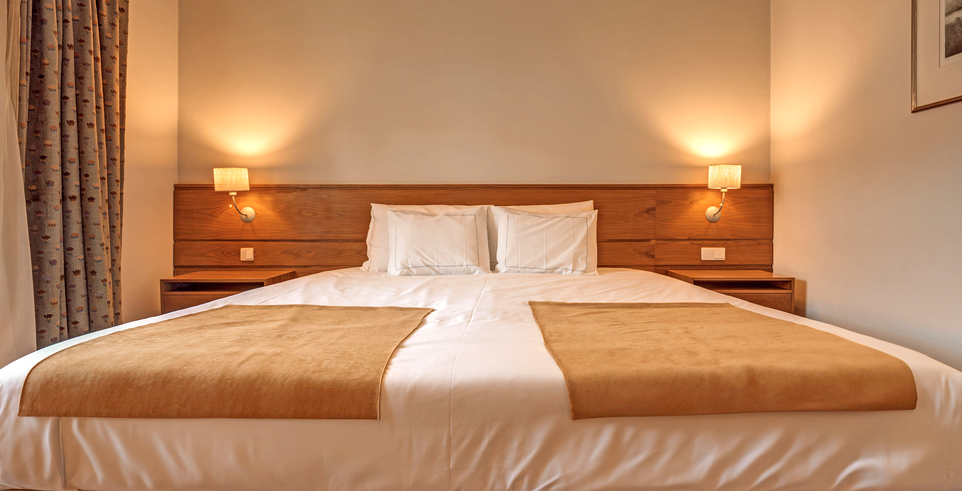 The Superior Family Room of The Pousada Ourém features a double bed with two bedside tables and two lamps