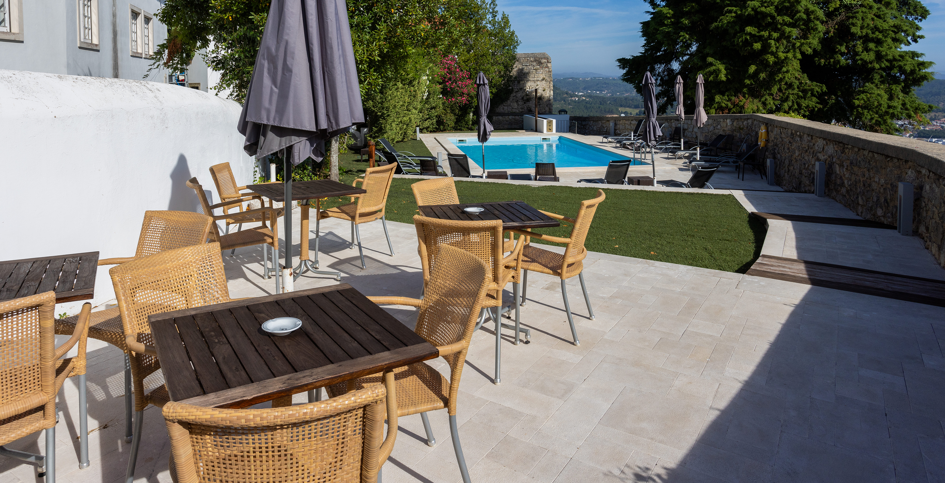 Terrace of Pousada Ourém near the outdoor pool with lawn around, sun loungers, and nature views