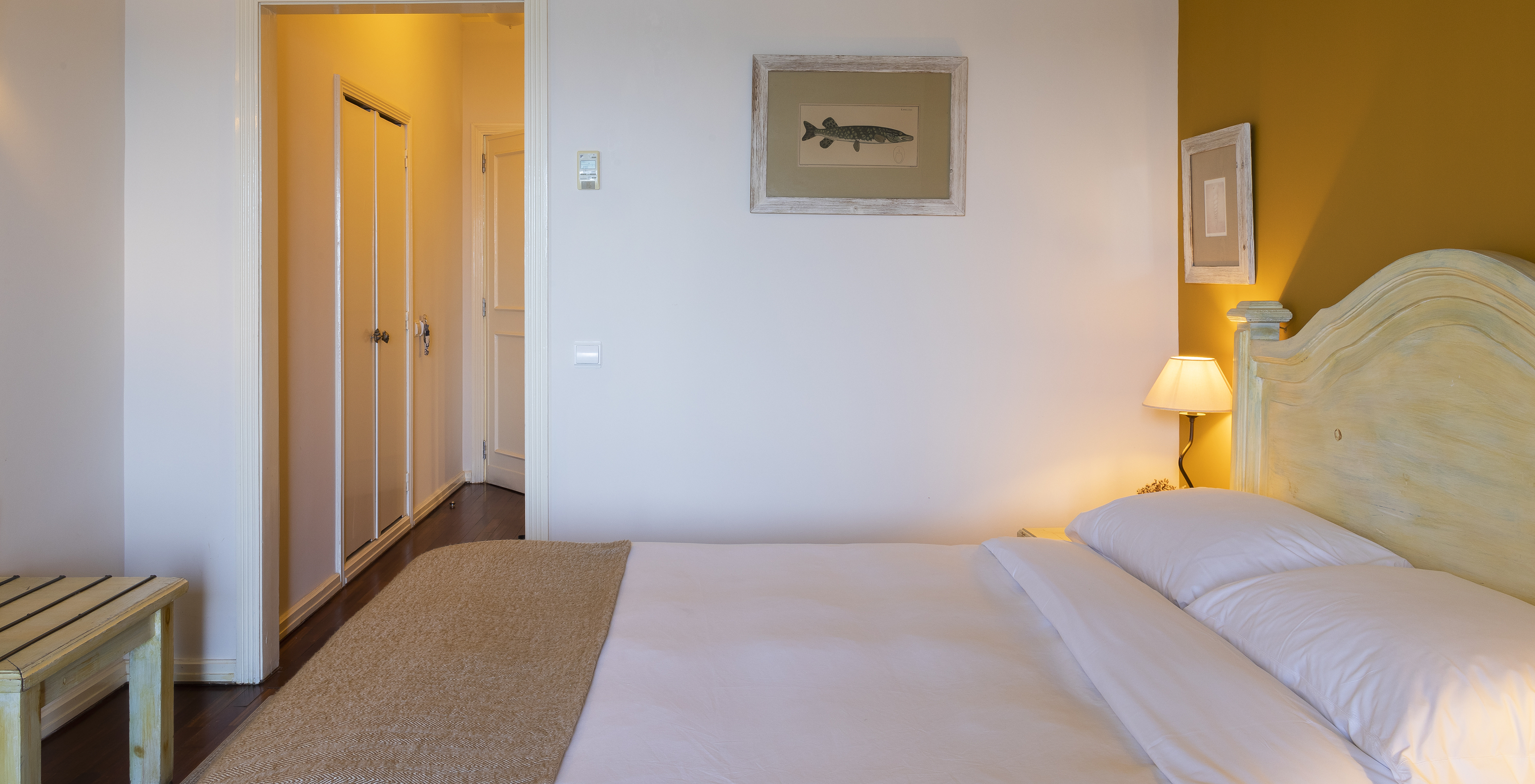 The Superior Ria View of The Ria Inn - Aveiro has a bed, a painting, a closet, and a luggage support area