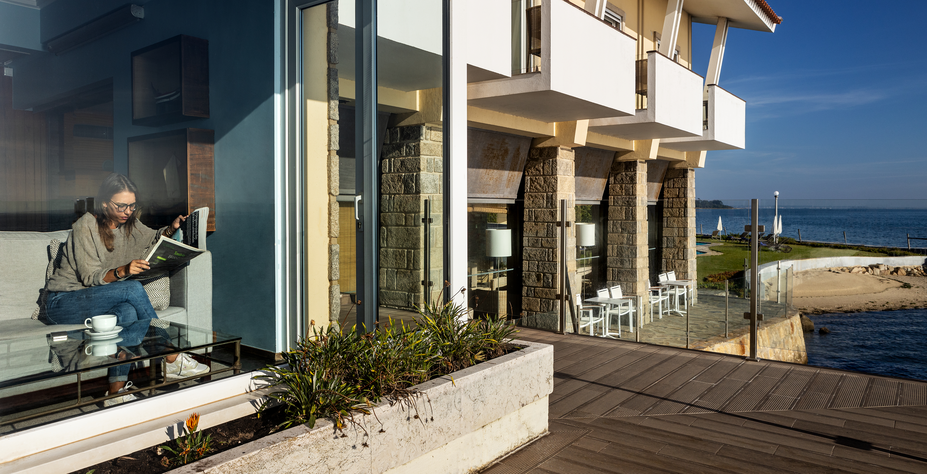 Facade of Pousada da Ria - Aveiro, where you can see the private beach and a person reading inside the inn