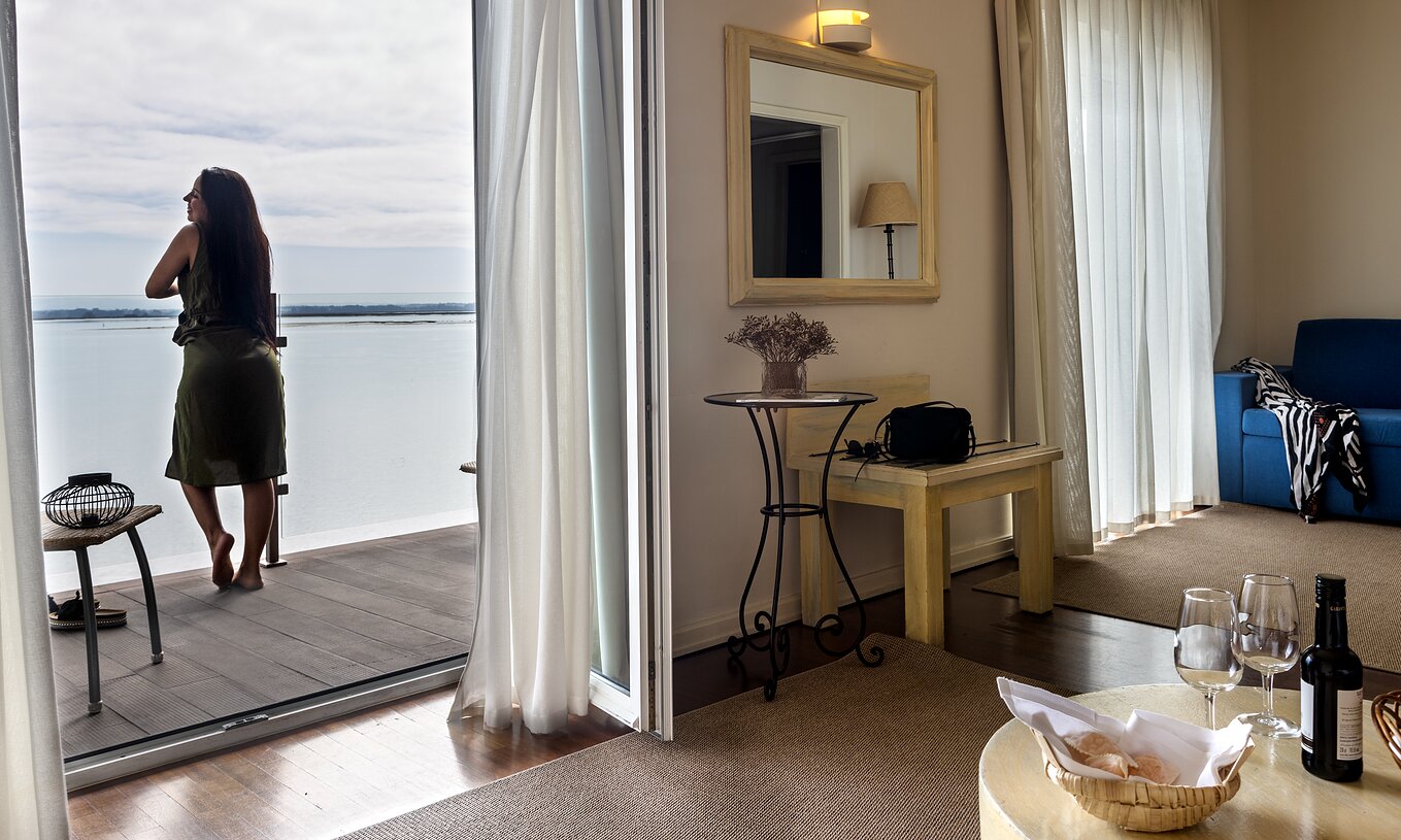 The Junior Suite of The Ria Inn - Aveiro has a living room with sofa, table, and a balcony with panoramic view of the ria