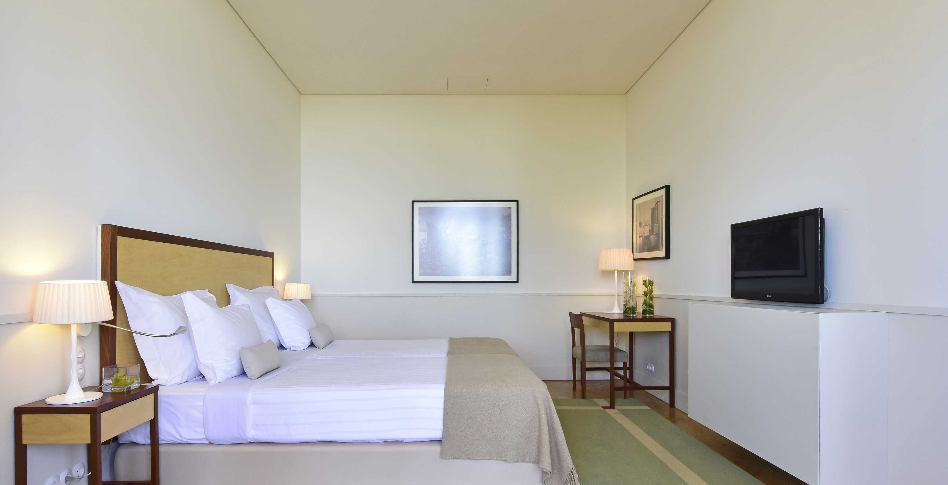 The Superior Room of The Serra da Estrela Inn has two beds and two bedside tables, a desk, and a TV