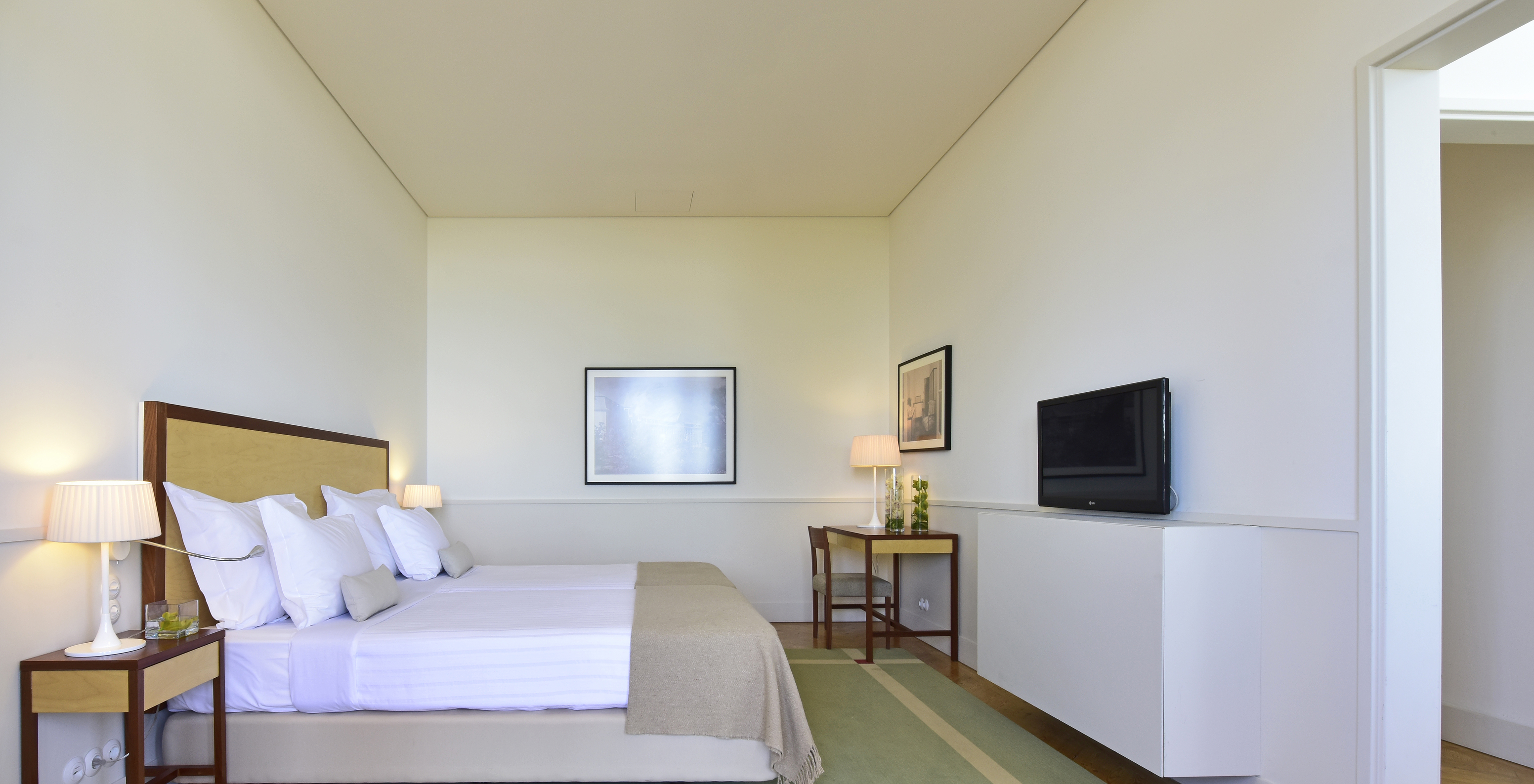 The Superior Family of The Pousada Serra da Estrela has a double bed, a television, a desk, and two paintings on the wall