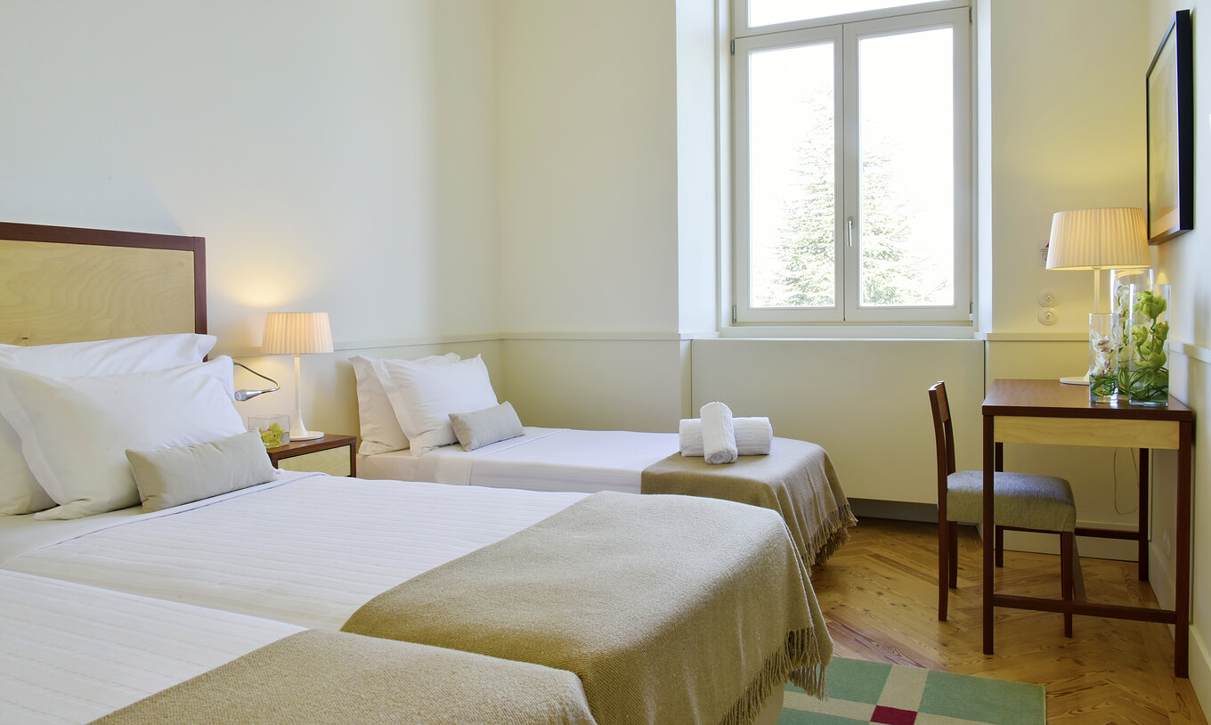 The Classic Family Room of The Serra da Estrela Inn has two beds and an extra bed, and a window with a view of the mountain
