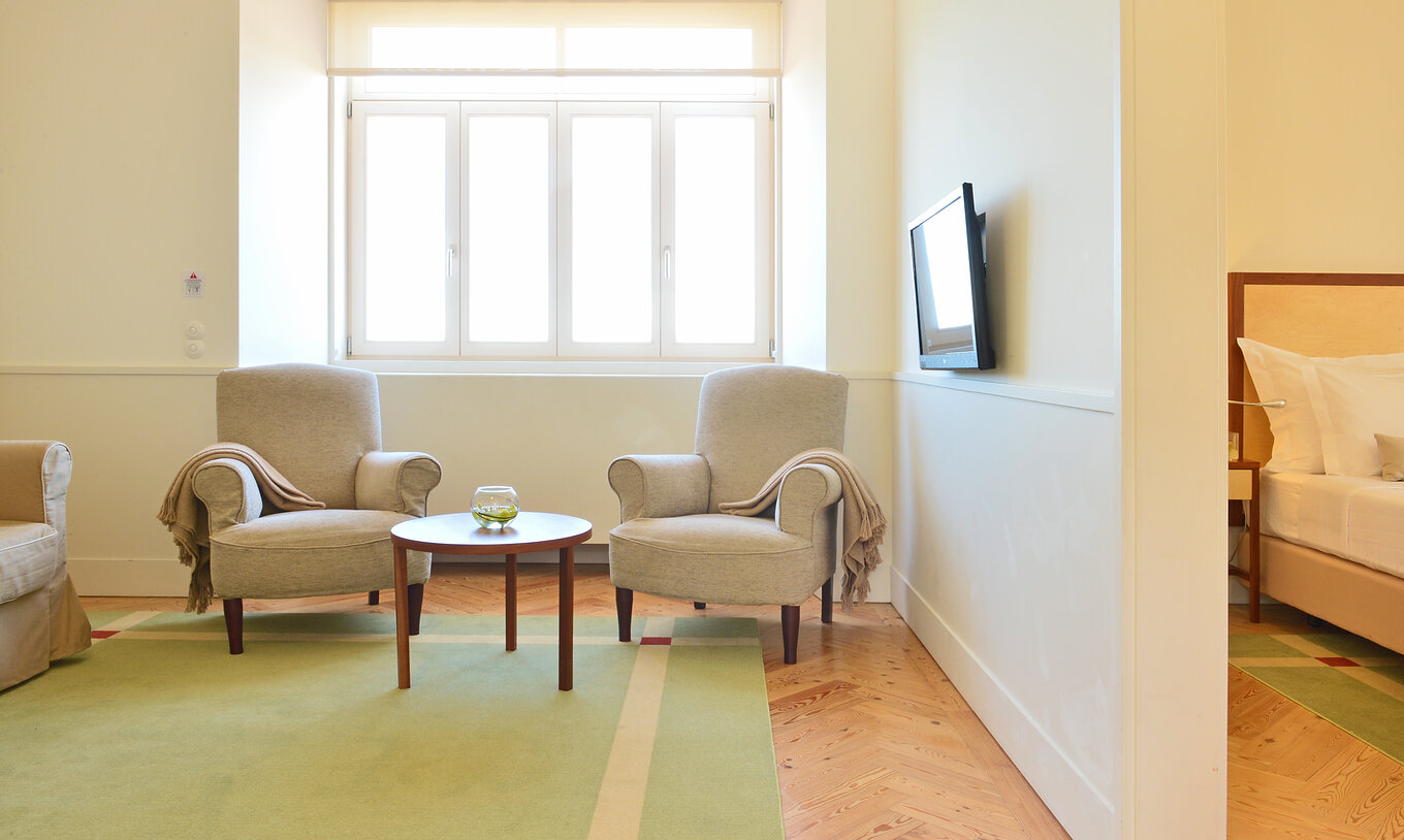 The Standard Suite of The Serra da Estrela Inn has a bedroom with a double bed and a living room with two armchairs and a TV