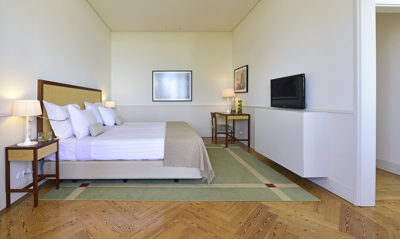 The Superior Family of The Pousada Serra da Estrela has a double bed, a television, a desk, and two paintings on the wall