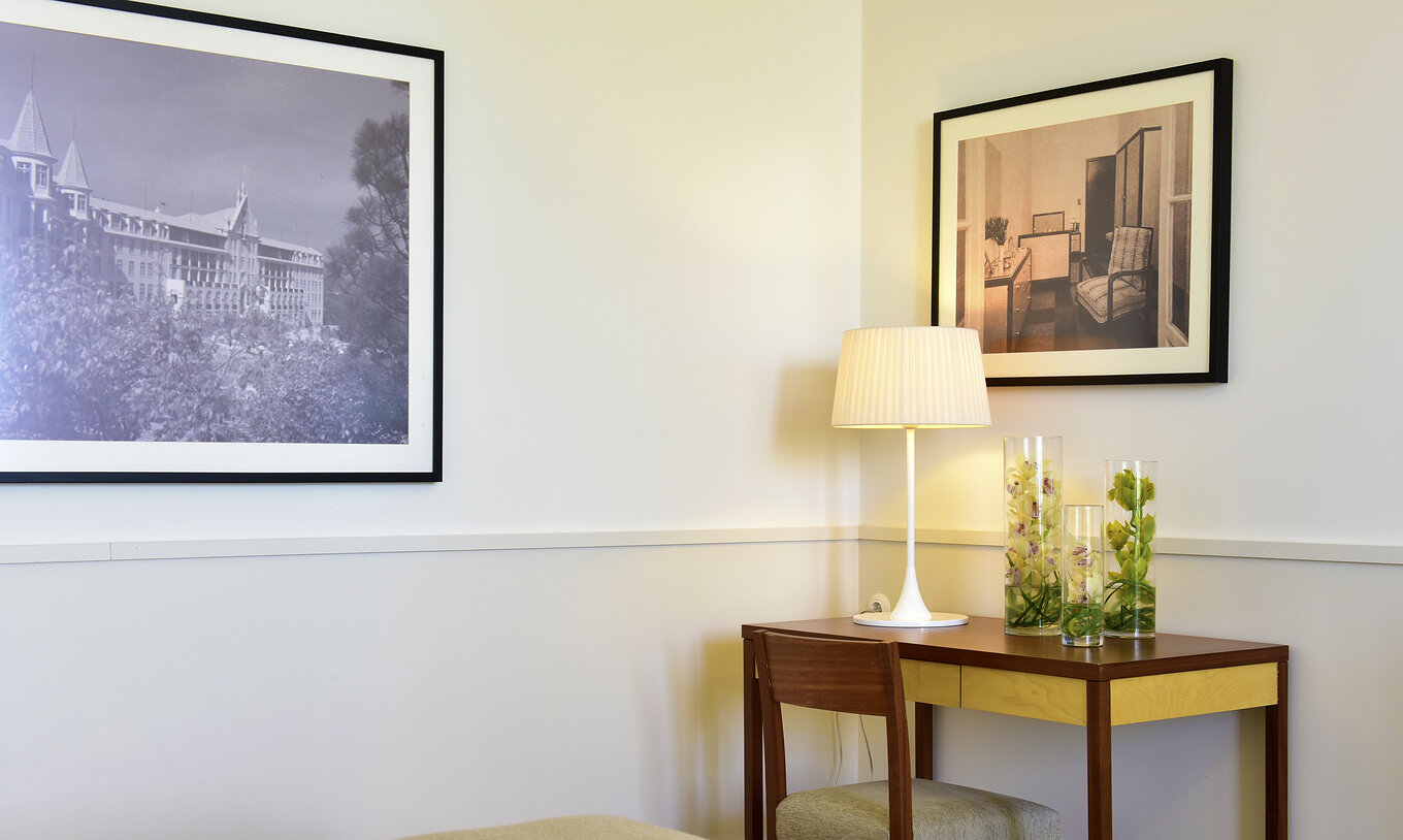 The Superior Room of The Serra da Estrela Inn has a desk and two paintings of the old sanatorium of Serra da Estrela