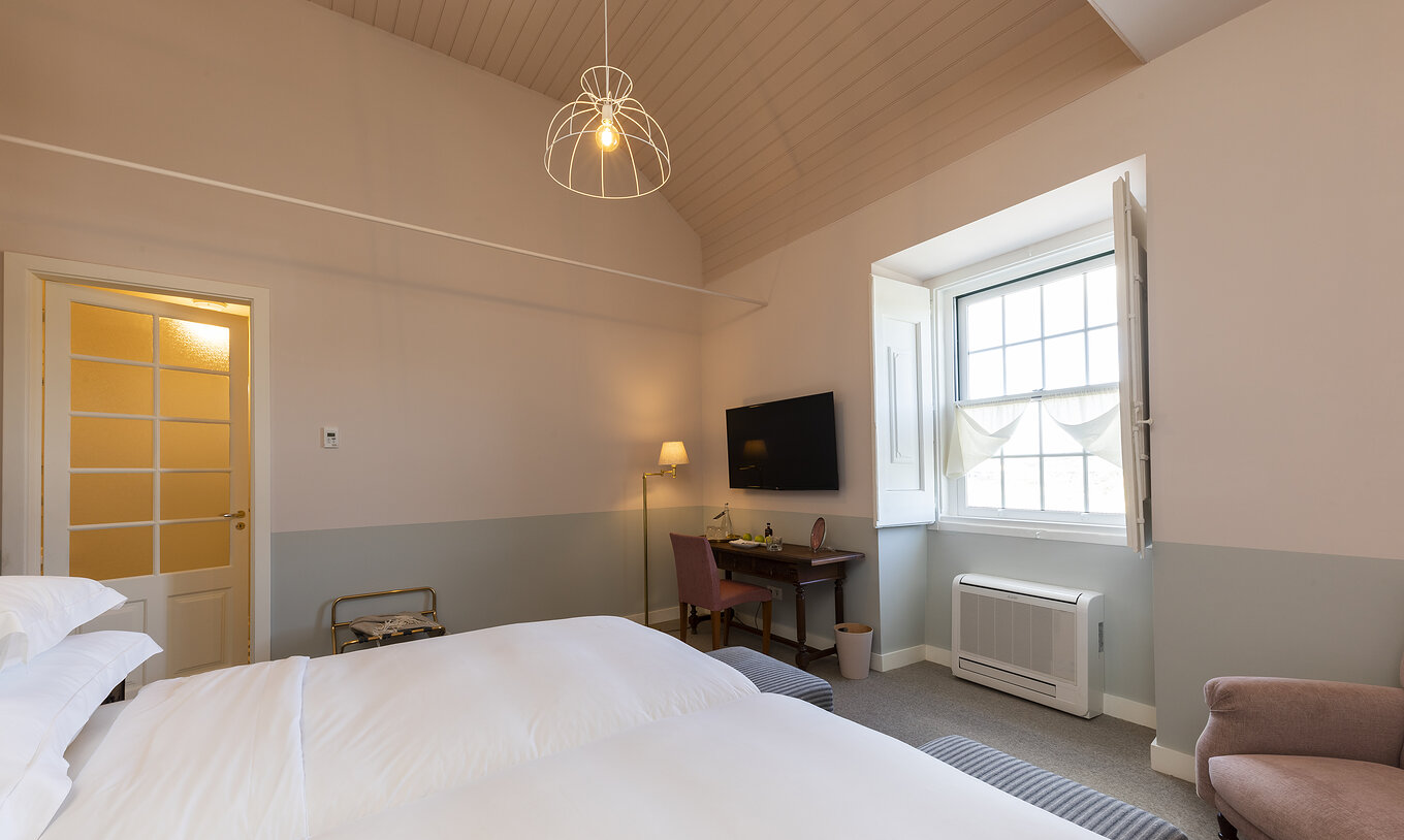 The Superior Room of The Pousada Vila Óbidos has a ceiling lamp and two beds with a window and a television in front