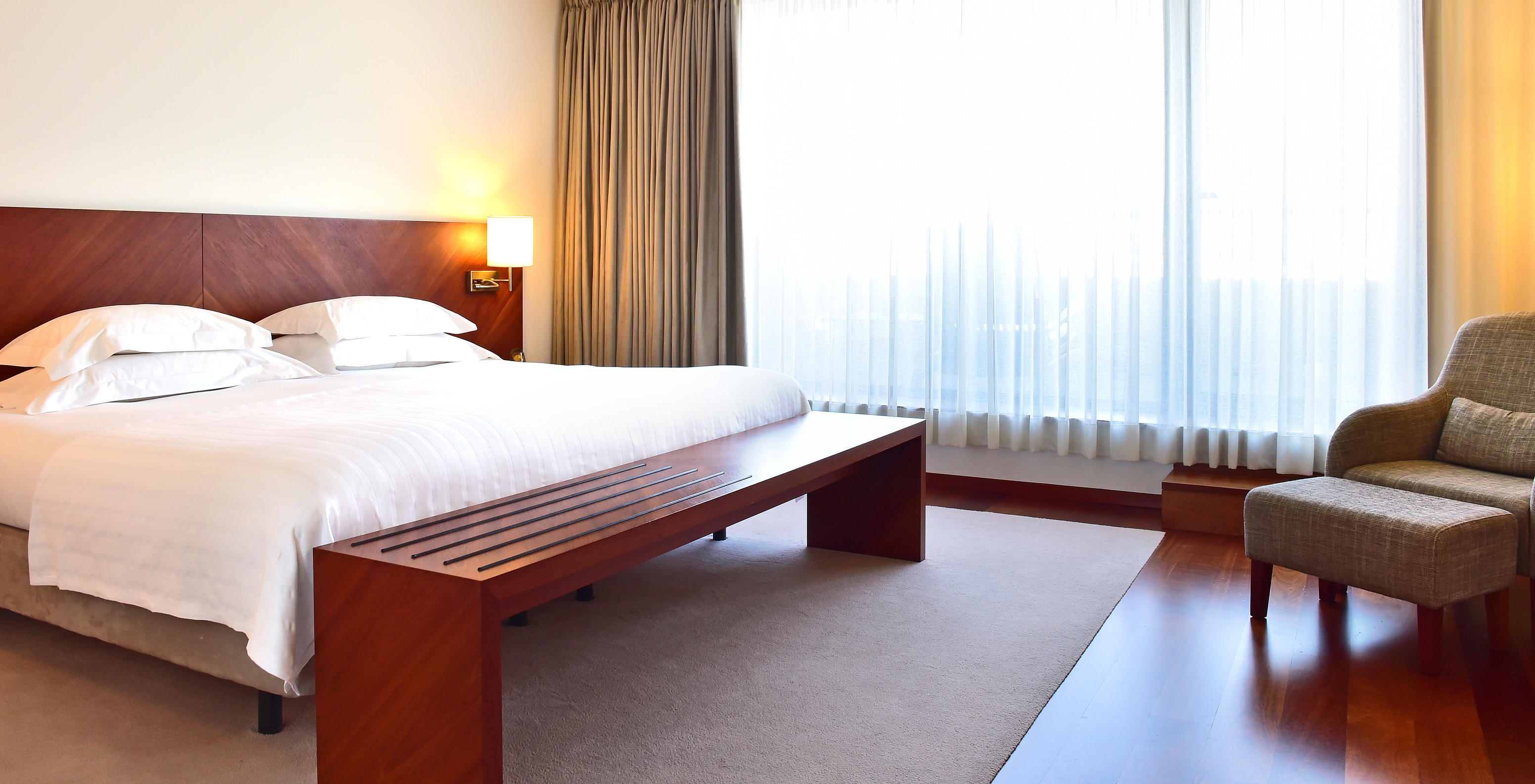 The Superior Room of the Pousada Viseu has a double bed, bedside table with lamp and an armchair