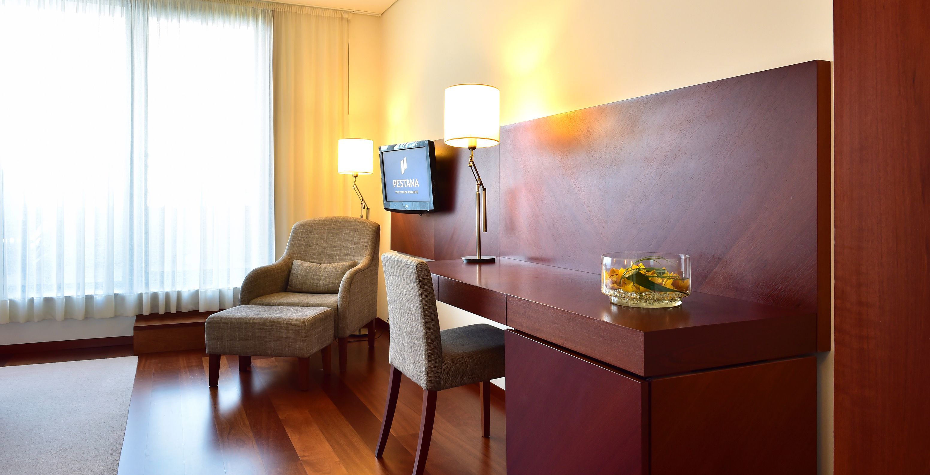 The Superior Room of the Pousada Viseu has a desk with chair and lamp, and an armchair beside