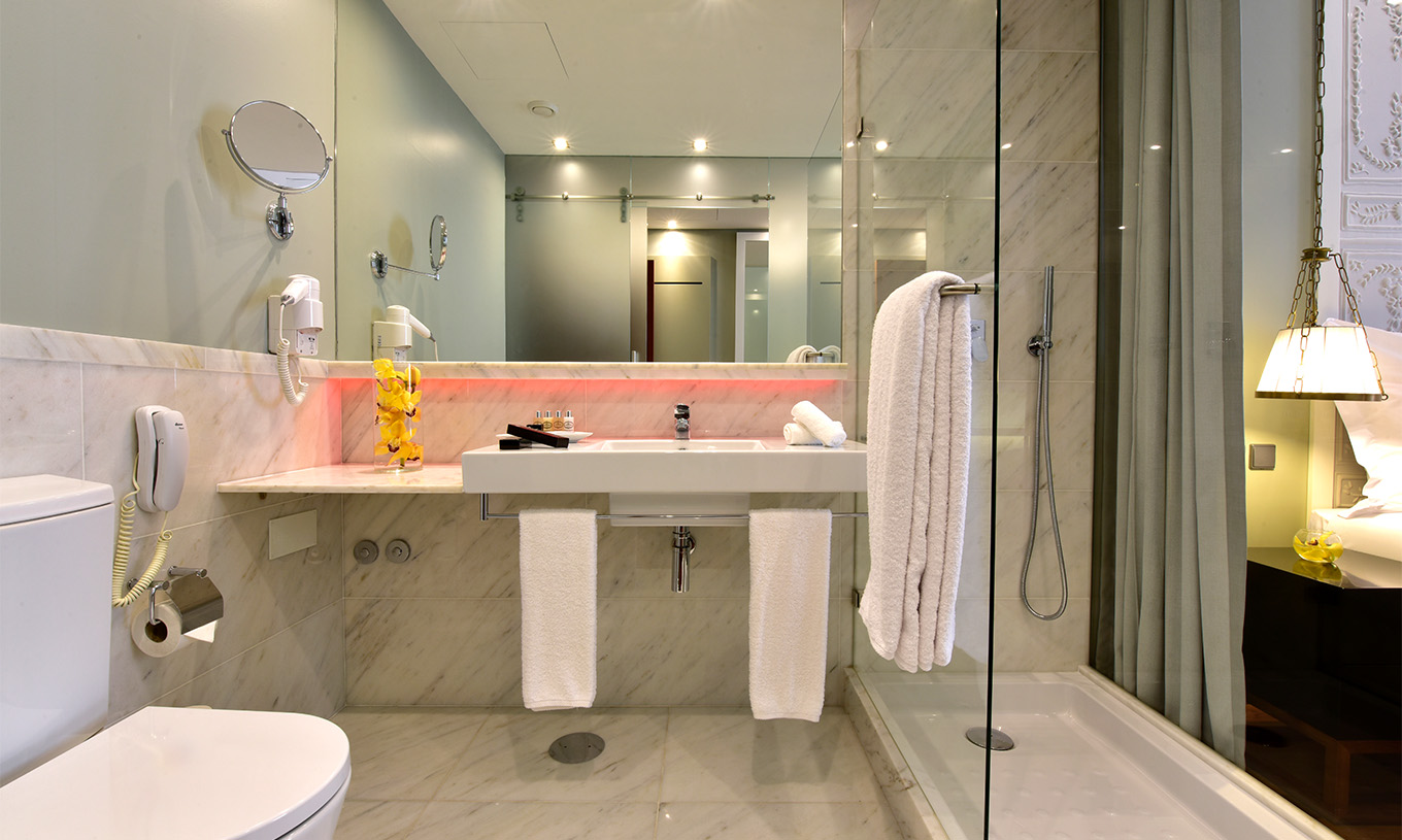 The Cozy Queen Size Bed of The Pousada Lisboa Praça do Comércio has a bathroom in white tones, shower, and red LEDs