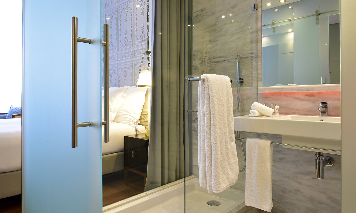 The Deluxe King Size Bed at Pousada de Lisboa Praça do Comércio has bathroom with shower, sink, mirror and white towel