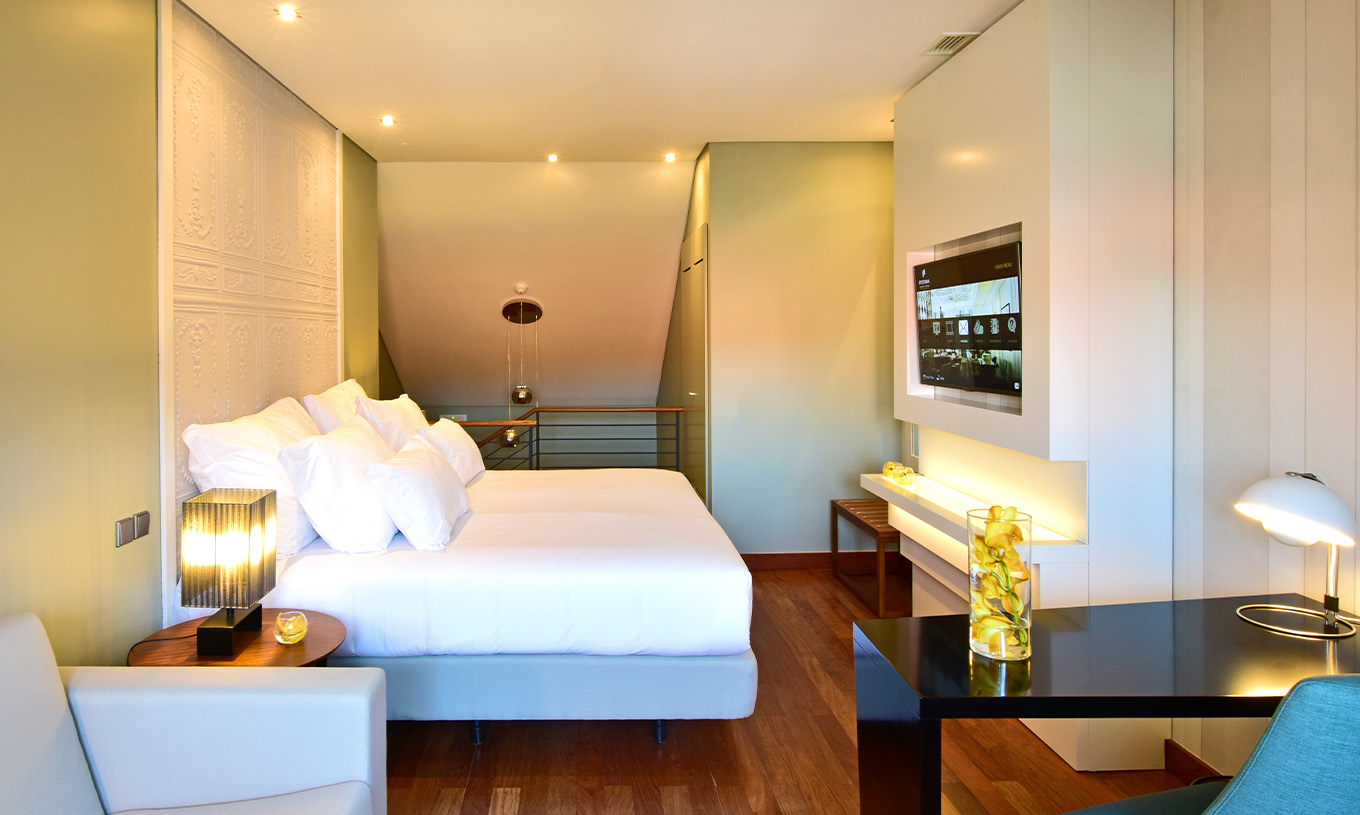 The Mezzanine King Size Bed of The Pousada Lisboa Praça do Comércio has a double bed, a television, a sofa, and a desk