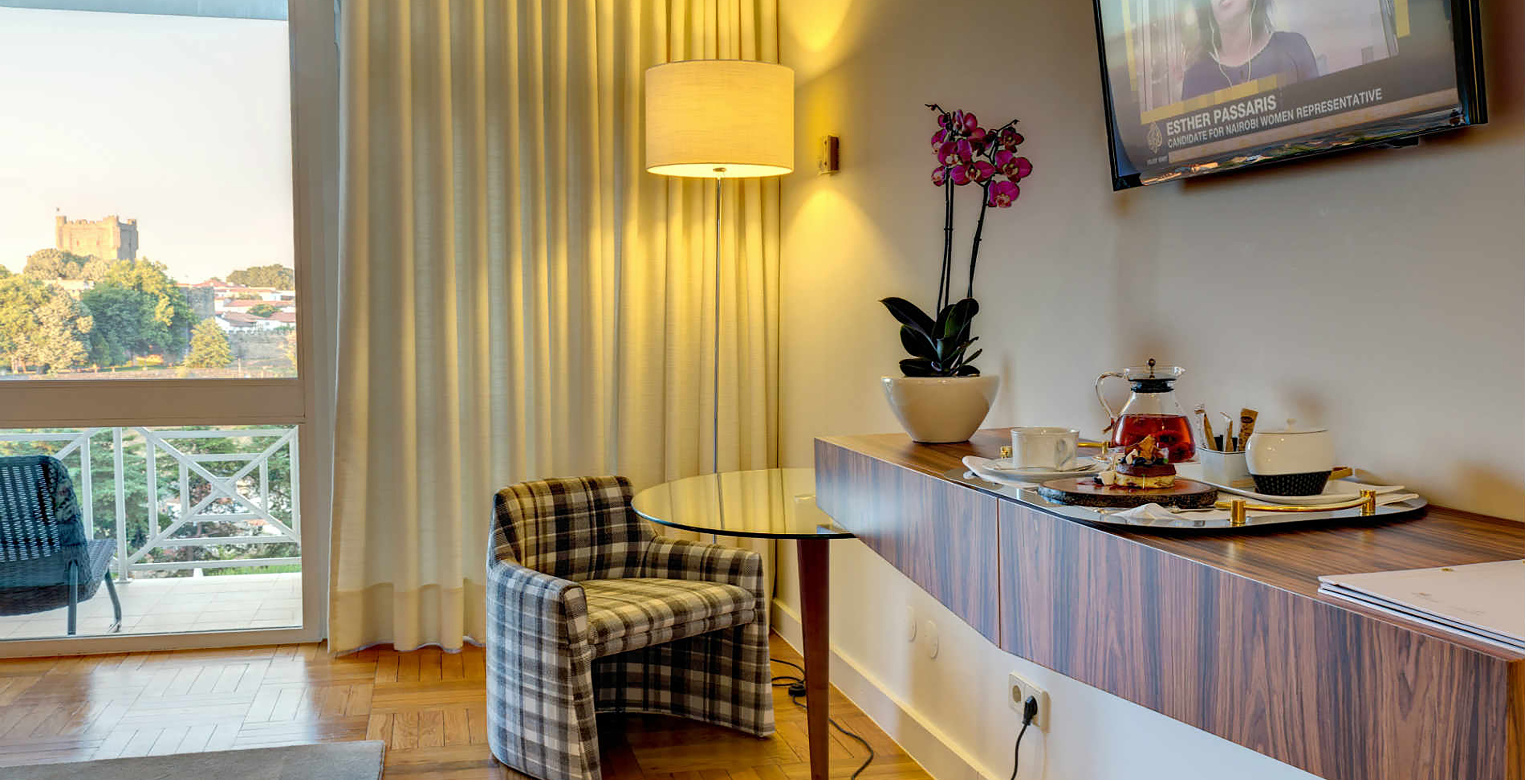 The Classic Room at Pousada Bragança has a TV, a hanging table with food, and an armchair with coffee table